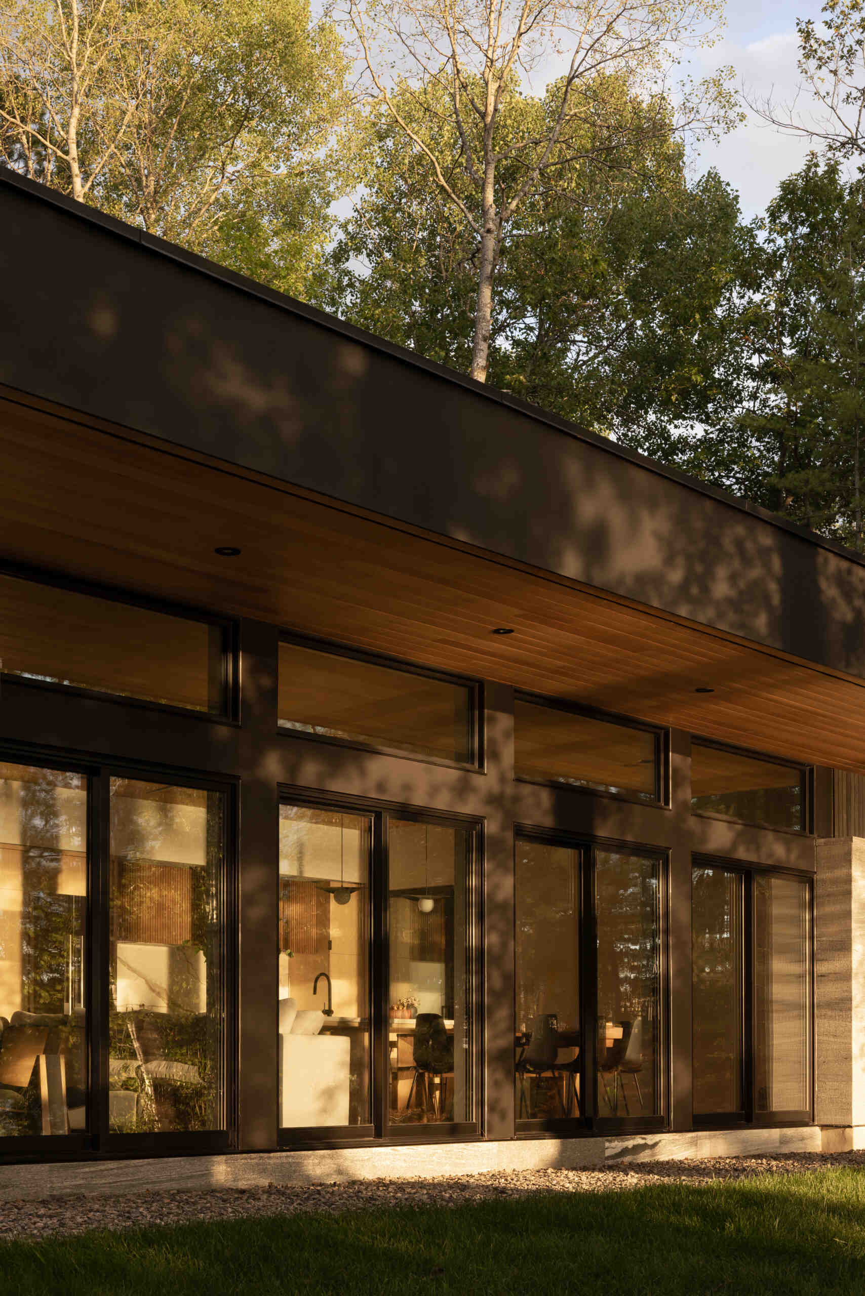Black timber cladding and glass define the exterior of this modern lake cottage, striking yet rooted in the forest.