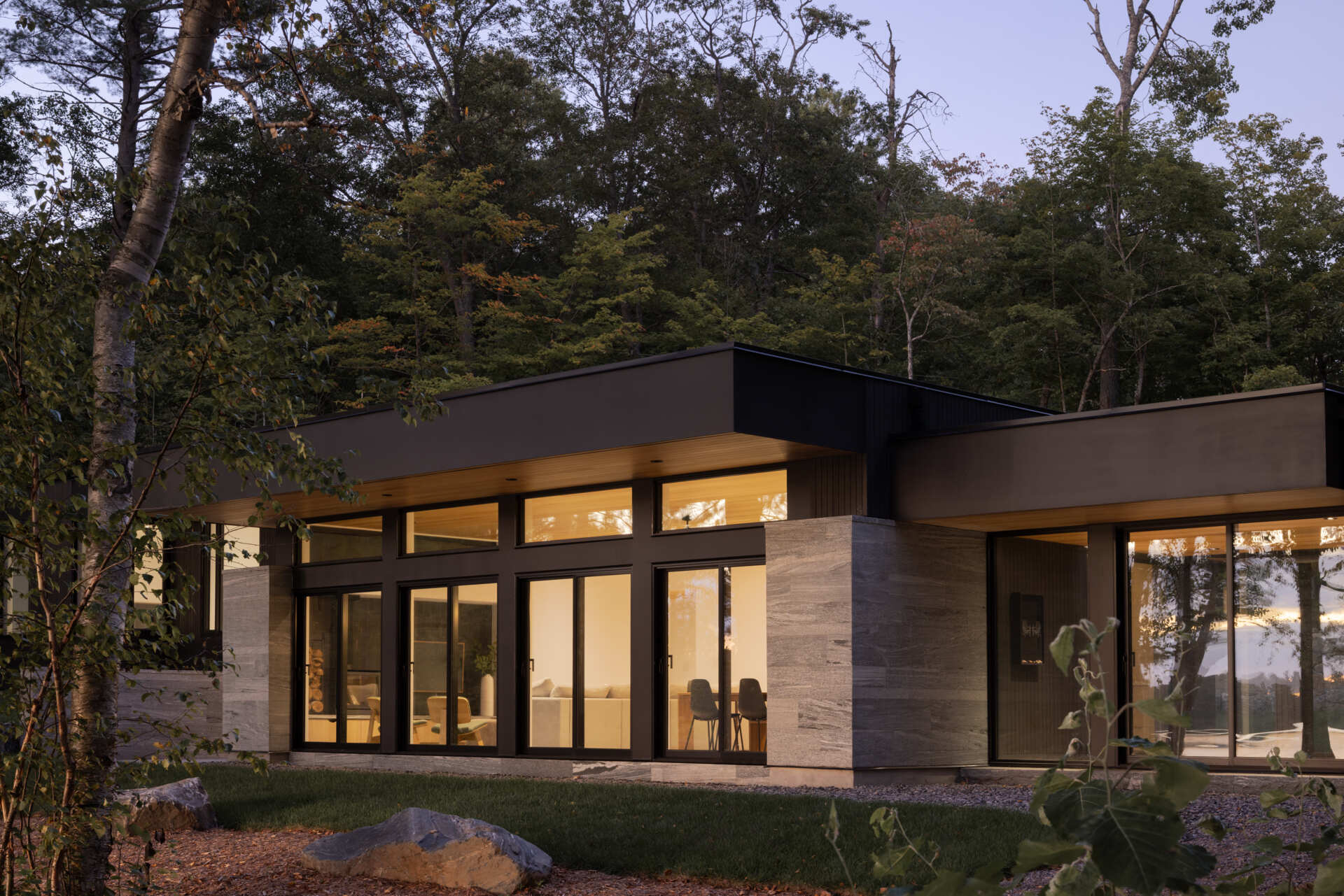 Black timber cladding and glass define the exterior of this modern lake cottage, striking yet rooted in the forest.