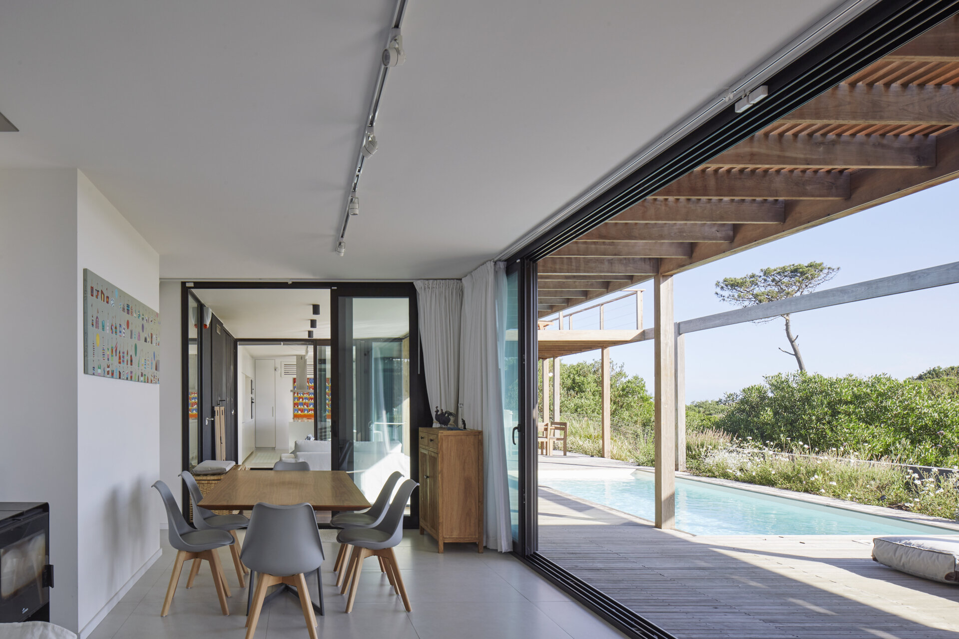 This prefabricated modular house, clad in wood, orientates each room, like the living room and dining area, towards the pool and beach.