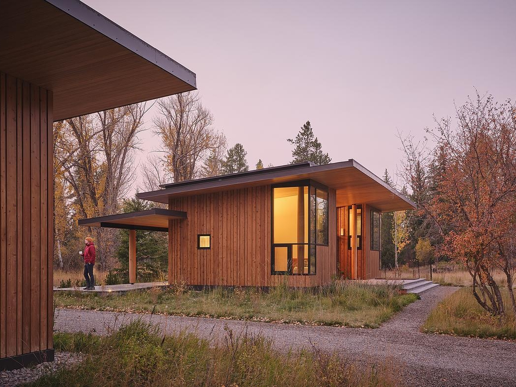 Timber curtain walls and warm plywood panels define the guest house’s modern yet inviting design.