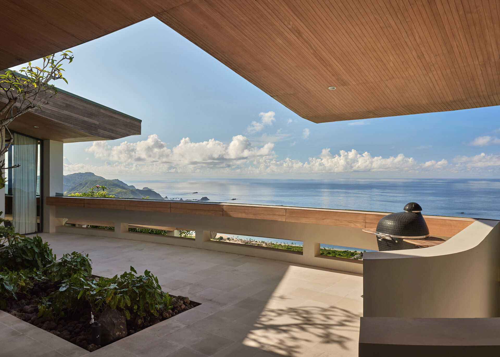 A terrace on the upper level of the home provides views that stretch over the ocean and hills, offering a peaceful space to pause and take in the surroundings.