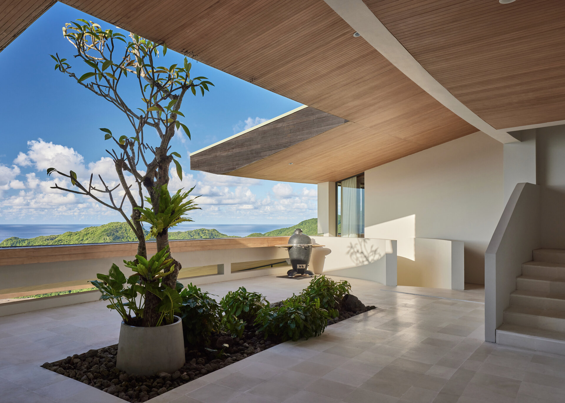 A terrace on the upper level of the home provides views that stretch over the ocean and hills, offering a peaceful space to pause and take in the surroundings.