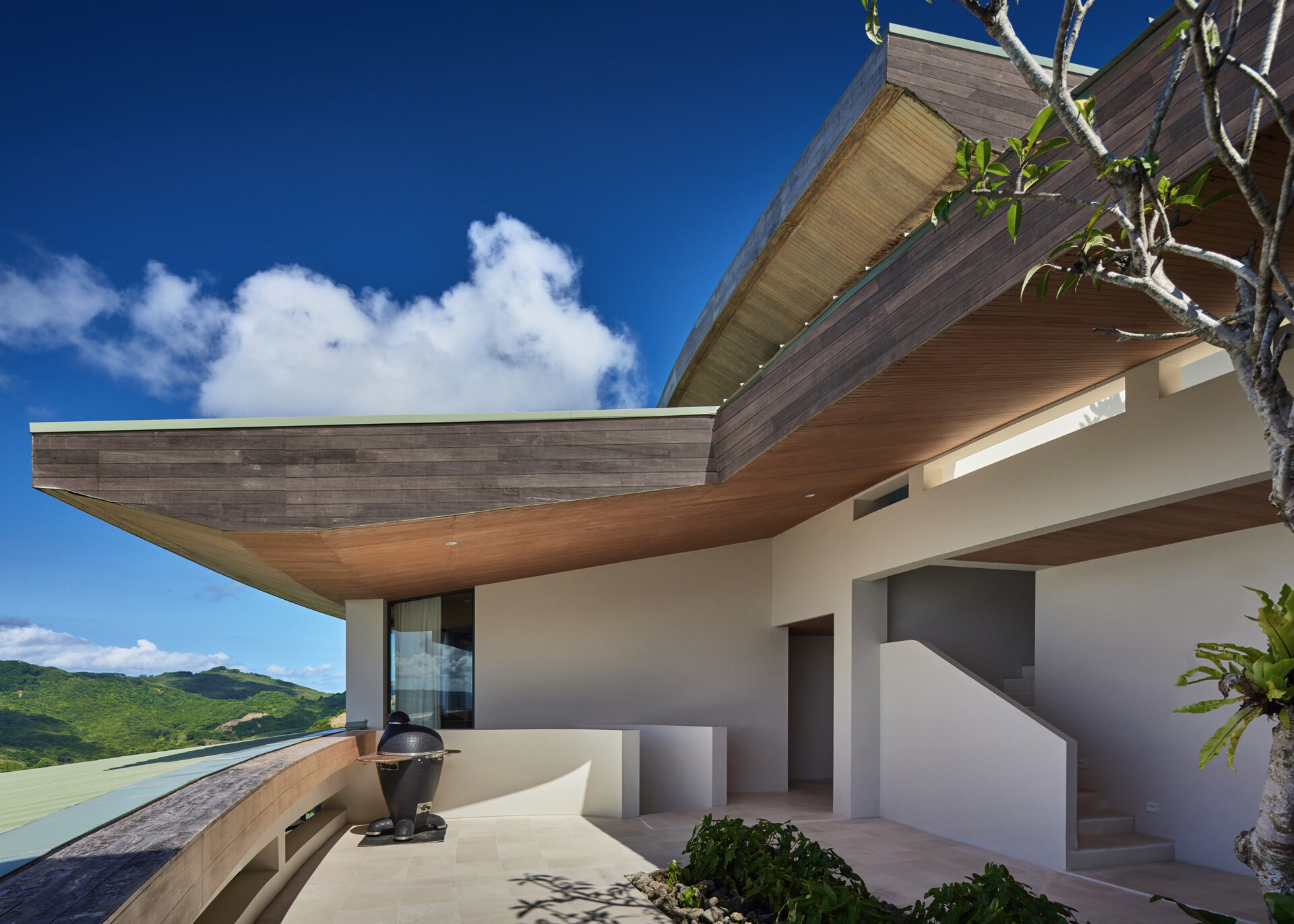 A terrace on the upper level of the home provides views that stretch over the ocean and hills, offering a peaceful space to pause and take in the surroundings.