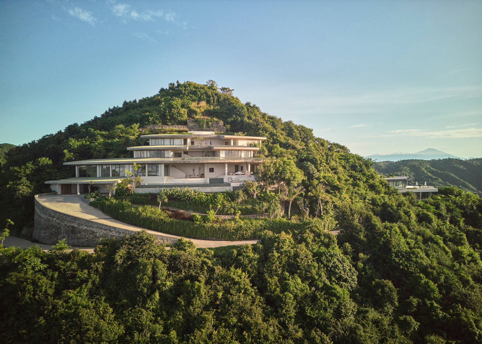 The home’s design is guided by the terrain. Its vertical layout adapts to the steep hillside, stacking functions across several levels. The geometry is based on concentric circles and radial segments, allowing the roofs and volumes to orient naturally with the hilltop.