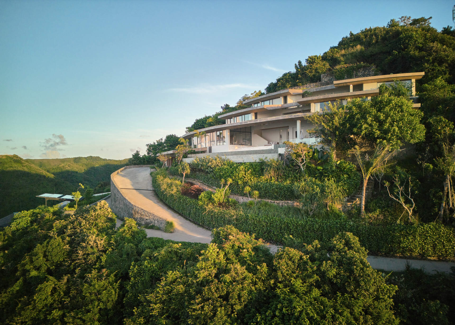 The home’s design is guided by the terrain. Its vertical layout adapts to the steep hillside, stacking functions across several levels. The geometry is based on concentric circles and radial segments, allowing the roofs and volumes to orient naturally with the hilltop.