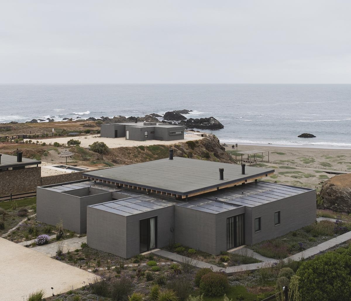 Wooden boxes and concrete walls come together in a minimalist coastal home design.