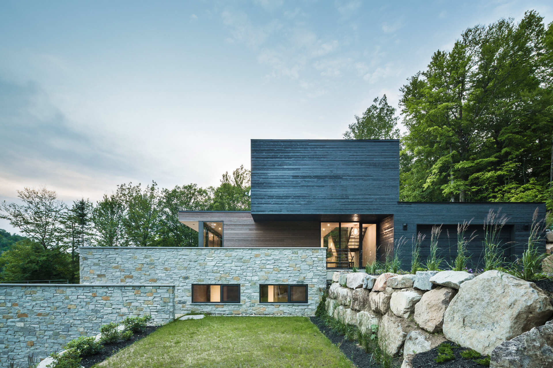 Terraced outdoor spaces framed by natural stone walls blend this modern home seamlessly into its rocky setting.