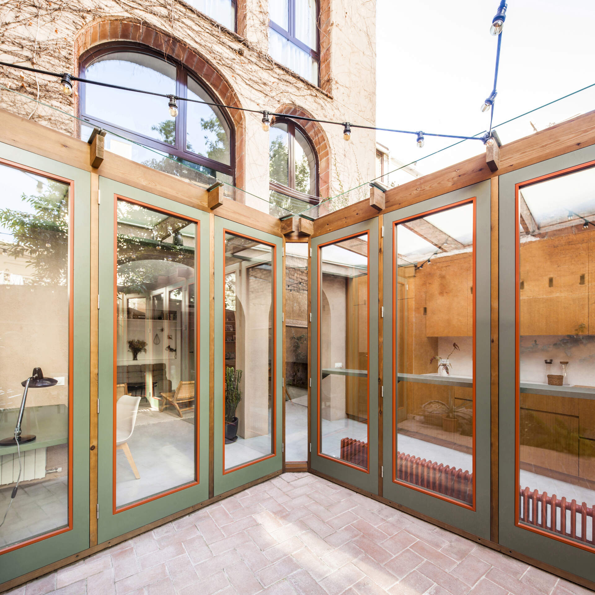 This house extension is conceived almost entirely as a transparent structure, built with wood and glass in the spirit of a greenhouse. Rather than blocking light, the glazed facade ensures that natural illumination continues to filter through the rest of the ground floor.