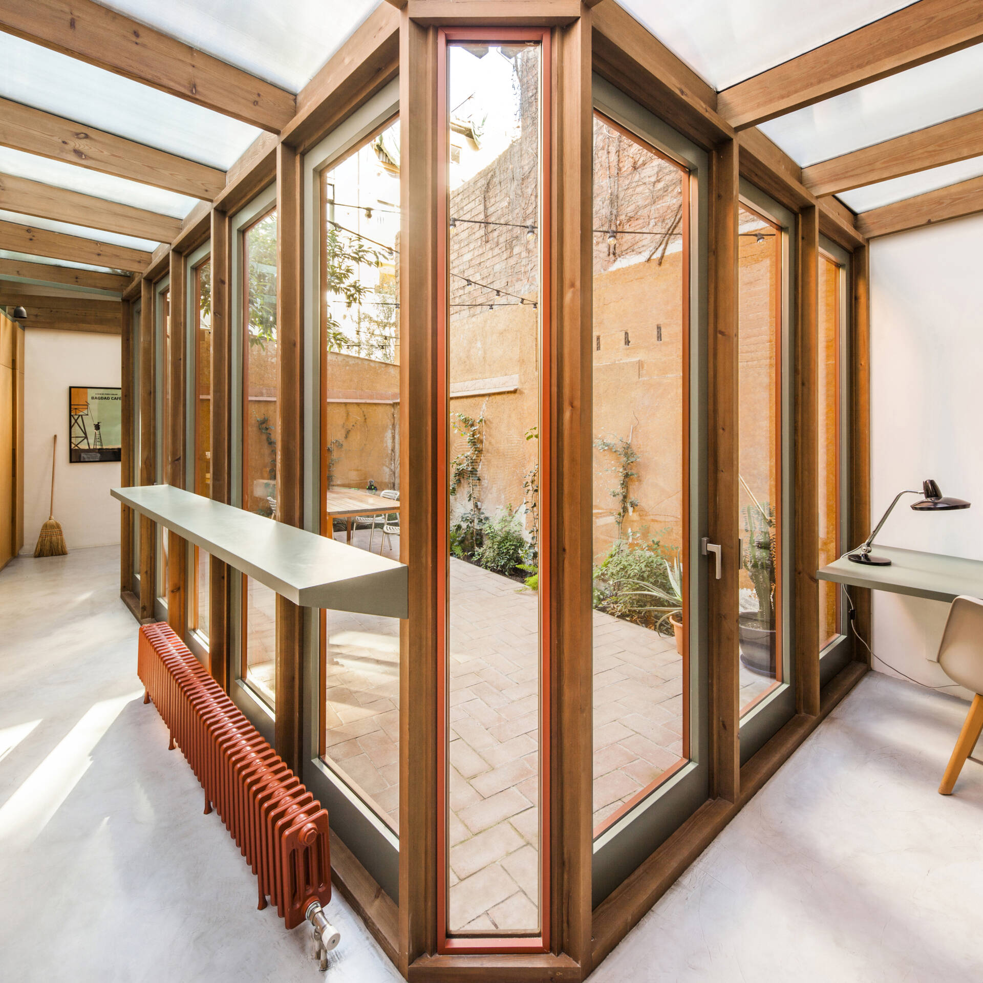 This house extension is conceived almost entirely as a transparent structure, built with wood and glass in the spirit of a greenhouse. Rather than blocking light, the glazed facade ensures that natural illumination continues to filter through the rest of the ground floor.