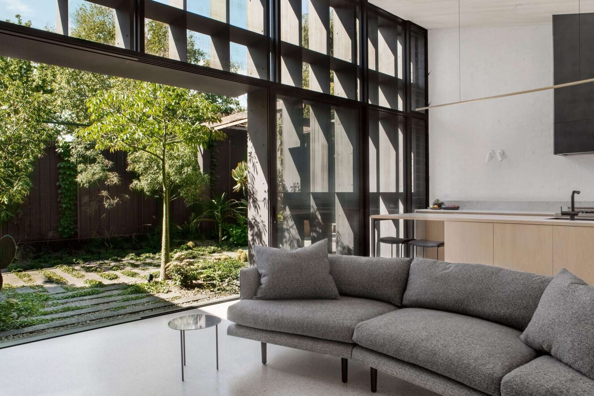 A curved grey sofa faces a black fireplace, paired with a wood bookshelf and industrial lighting.