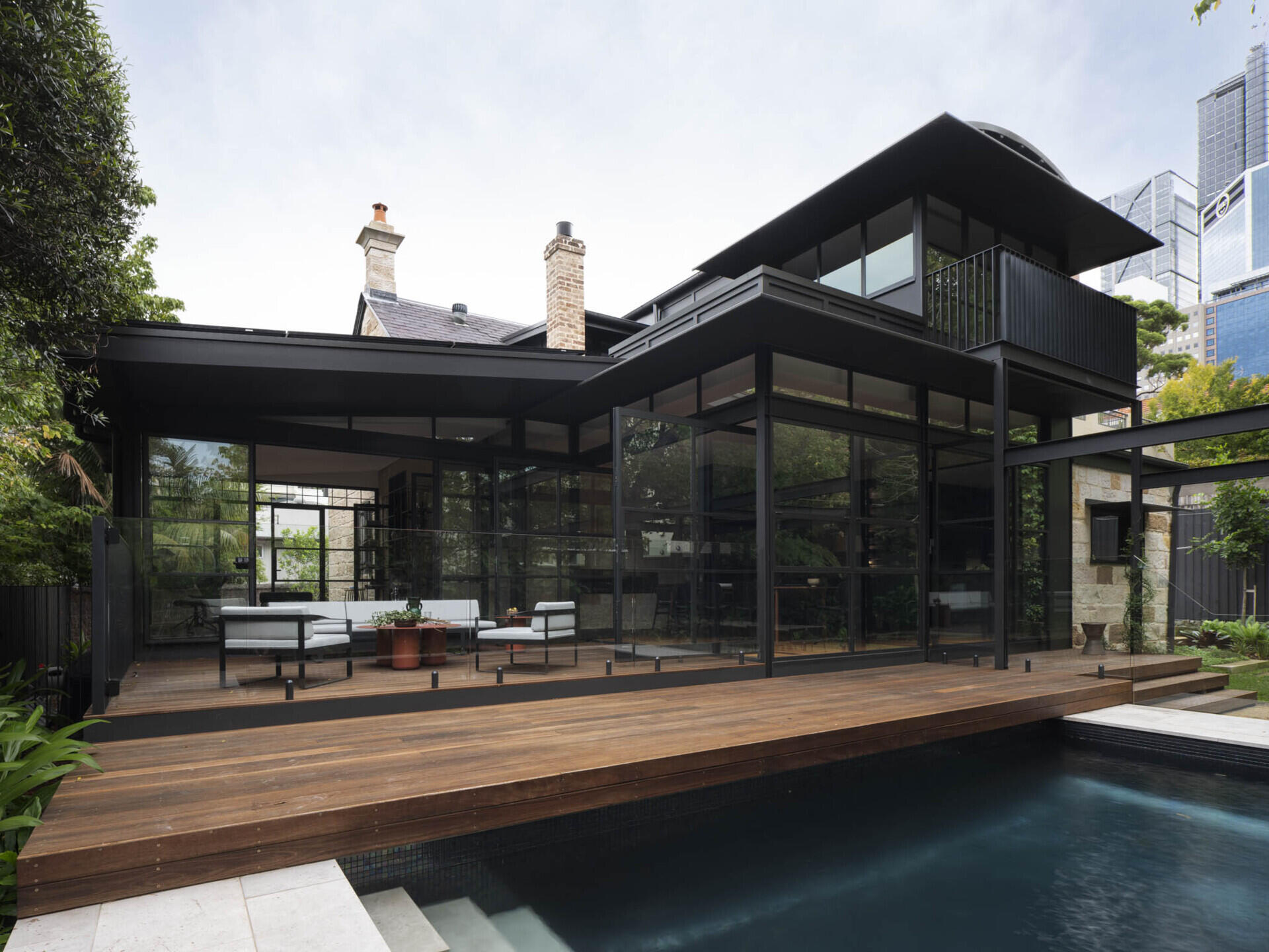 Steel-framed glazing leads to sheltered zones that frame leafy views while the refurbished pool made outdoor living part of the daily experience.