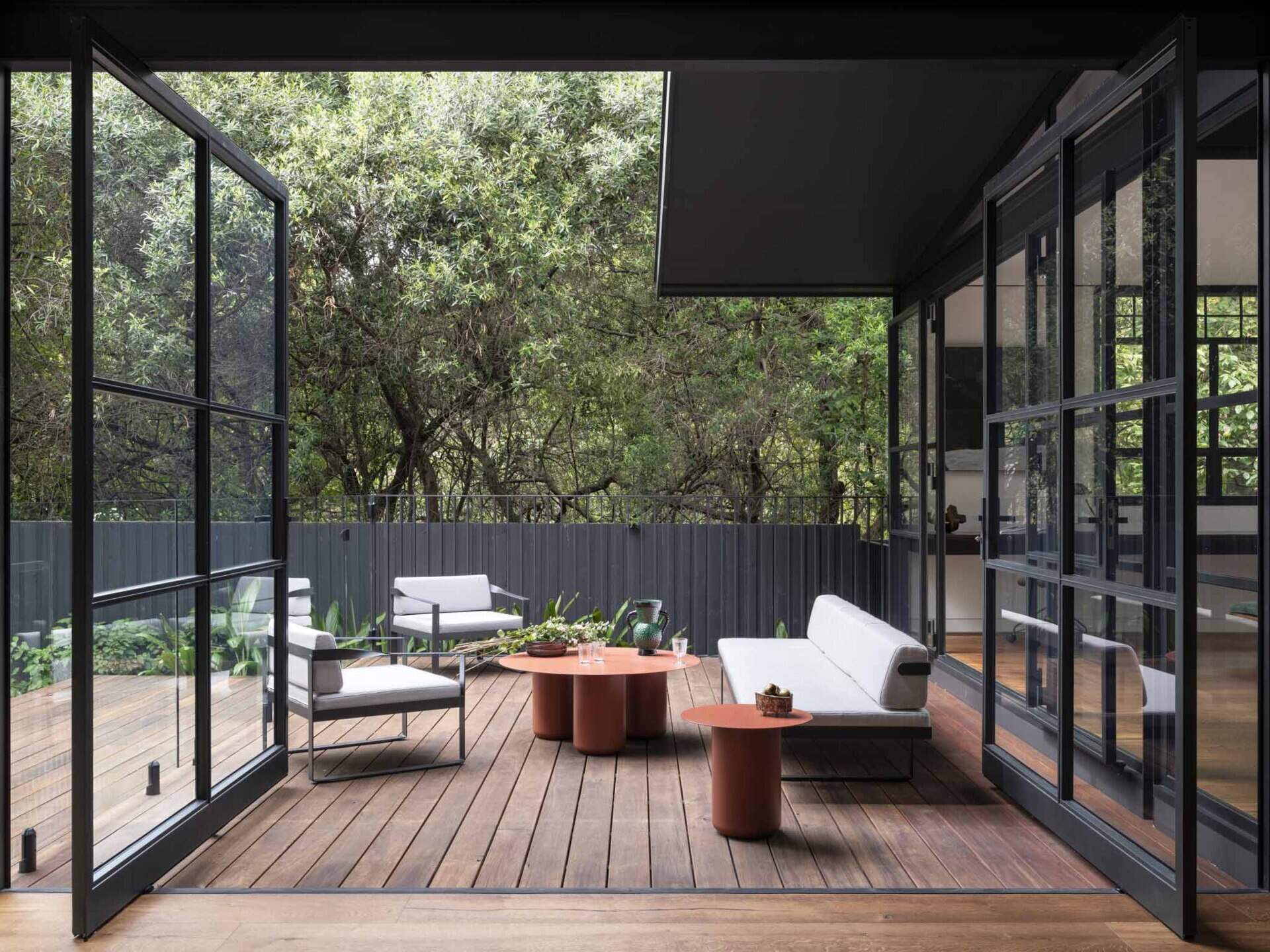 Steel-framed glazing leads to sheltered zones that frame leafy views while the refurbished pool made outdoor living part of the daily experience.