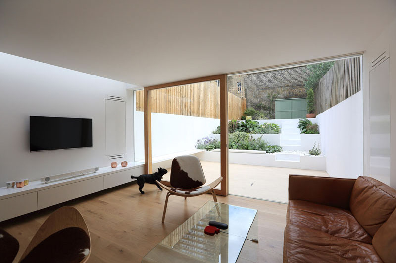 Built-in furniture now runs the length of the new living room, extending seamlessly to the outdoor patio. This continuity of design blurs the boundary between indoors and outdoors, creating a cohesive space for both daily living and entertaining. A custom sliding door ensures the maximum amount of natural light reaches inside, while also providing easy access to the garden.