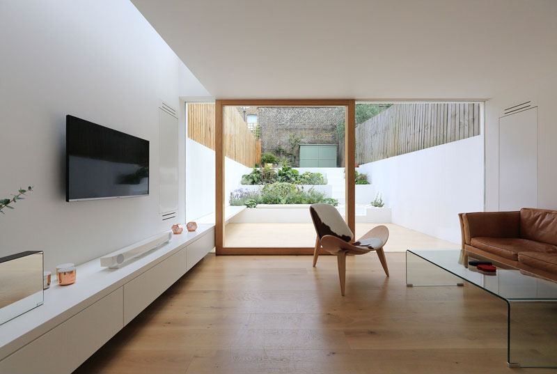 Built-in furniture now runs the length of the new living room, extending seamlessly to the outdoor patio. This continuity of design blurs the boundary between indoors and outdoors, creating a cohesive space for both daily living and entertaining. A custom sliding door ensures the maximum amount of natural light reaches inside, while also providing easy access to the garden.