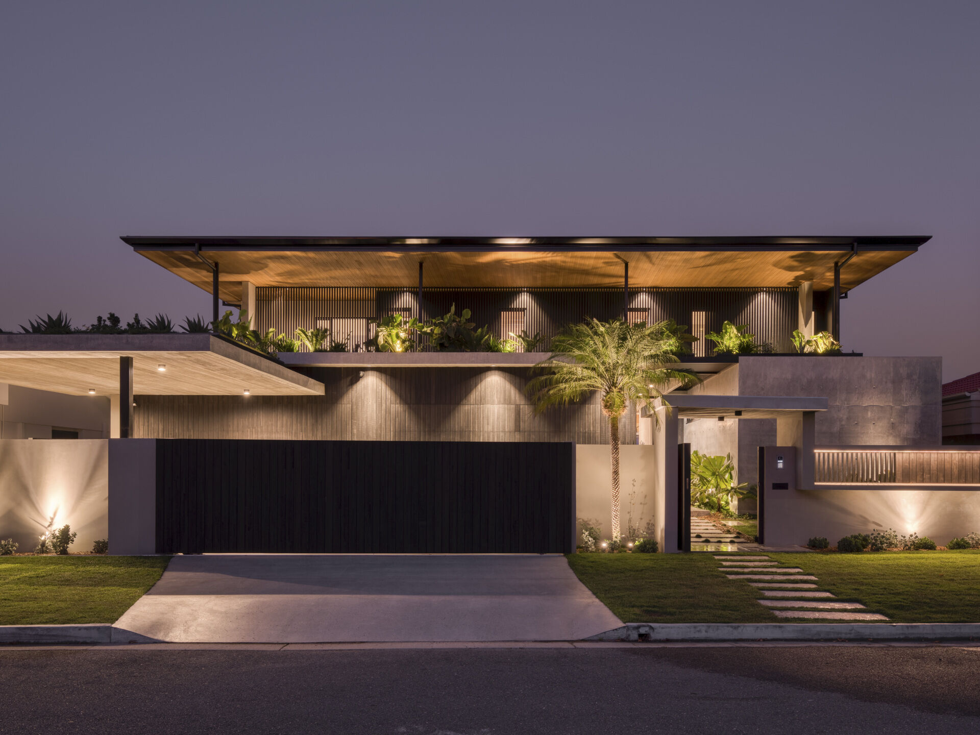 The western facade makes a bold first impression. Its monolithic form shields the home from the harsh afternoon sun while sculpting a striking architectural identity. Deep overhangs and battened screens soften the edges, while rooftop gardens introduce greenery at every level.