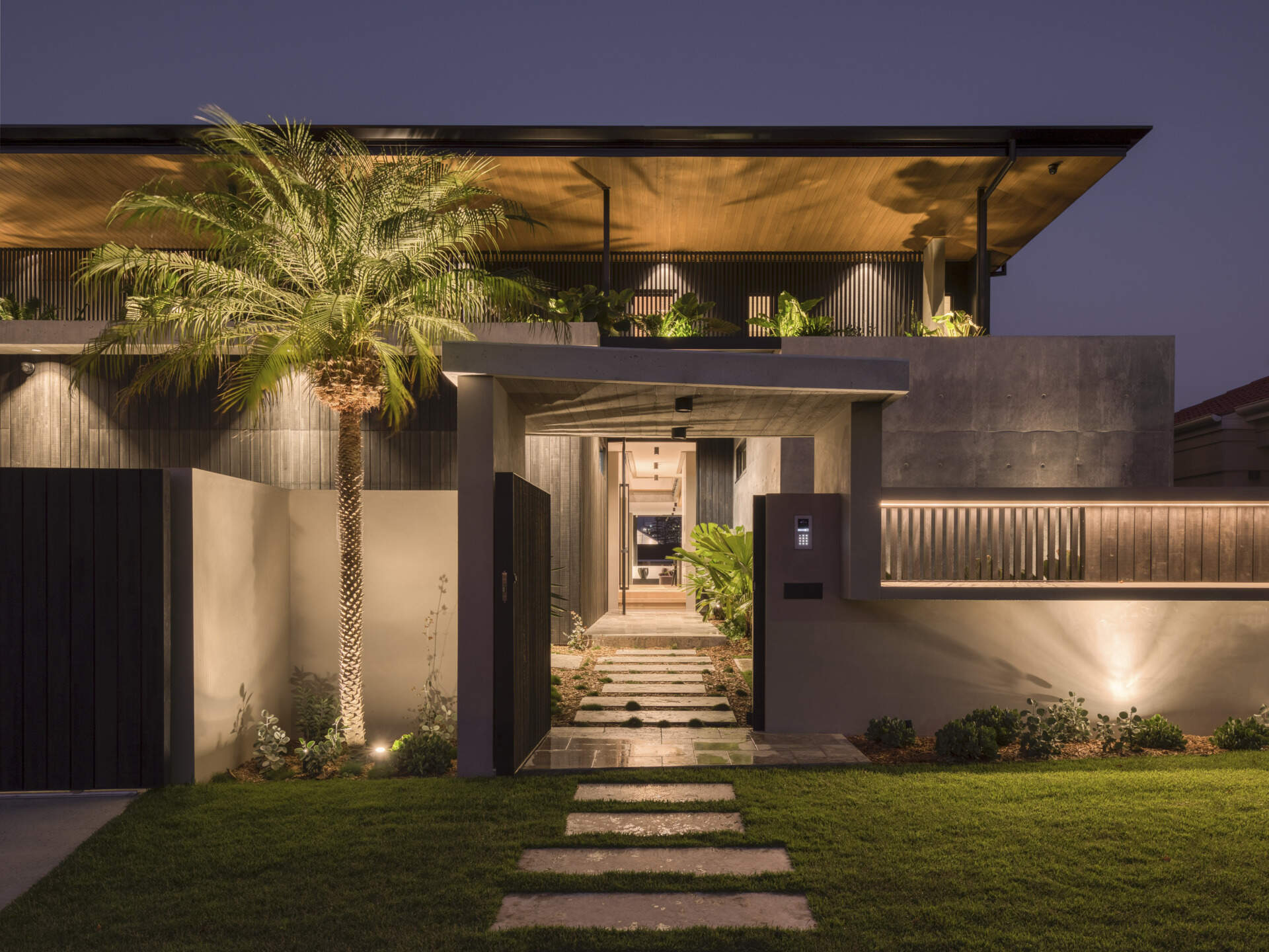 The entryway feels both private and welcoming, leading guests from a sheltered threshold into the heart of the house. The garage is integrated seamlessly, supporting the family’s daily life without interrupting the architectural flow.