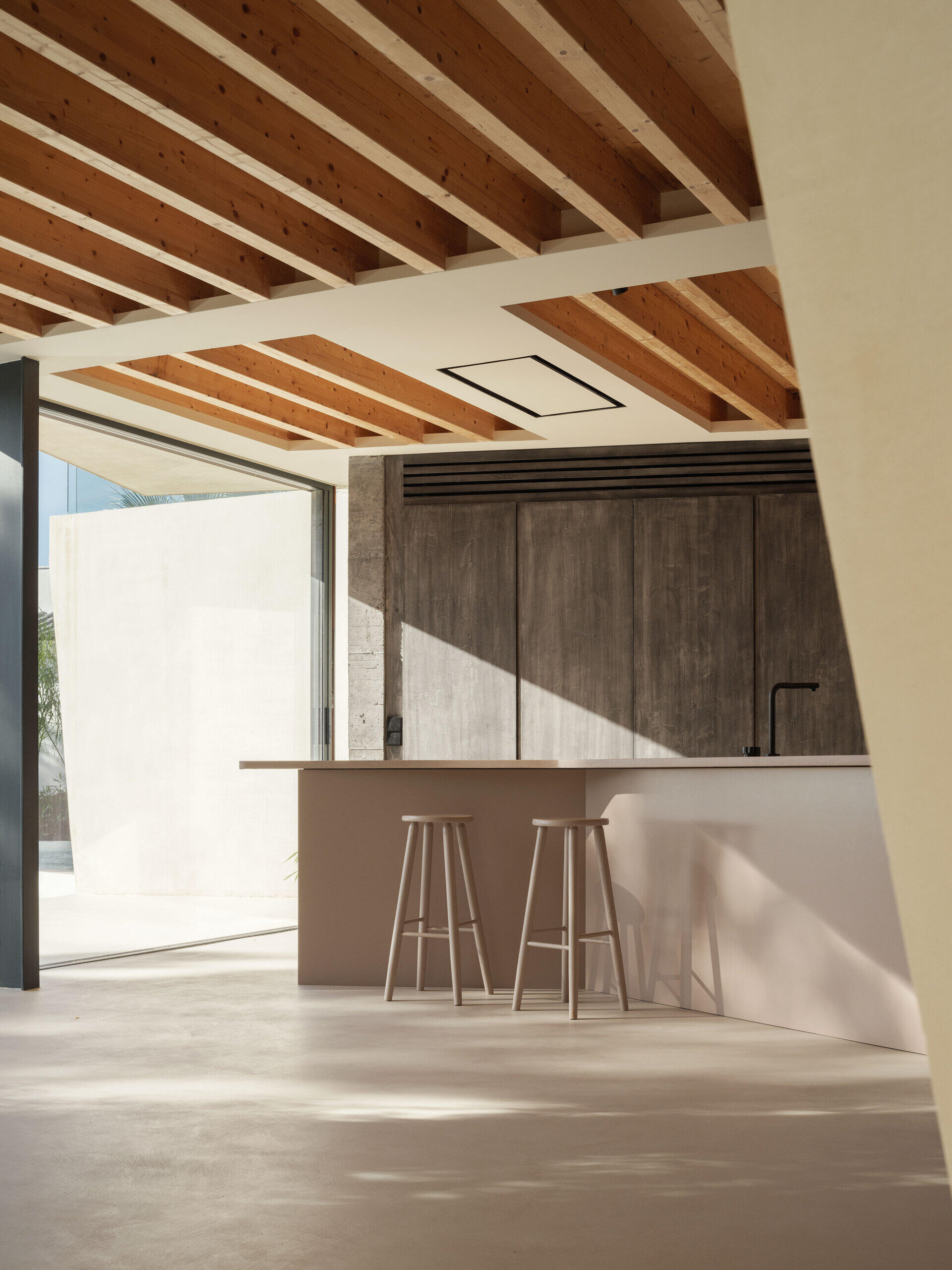 A minimalist kitchen design with an island that reflects the angled shape of the house.
