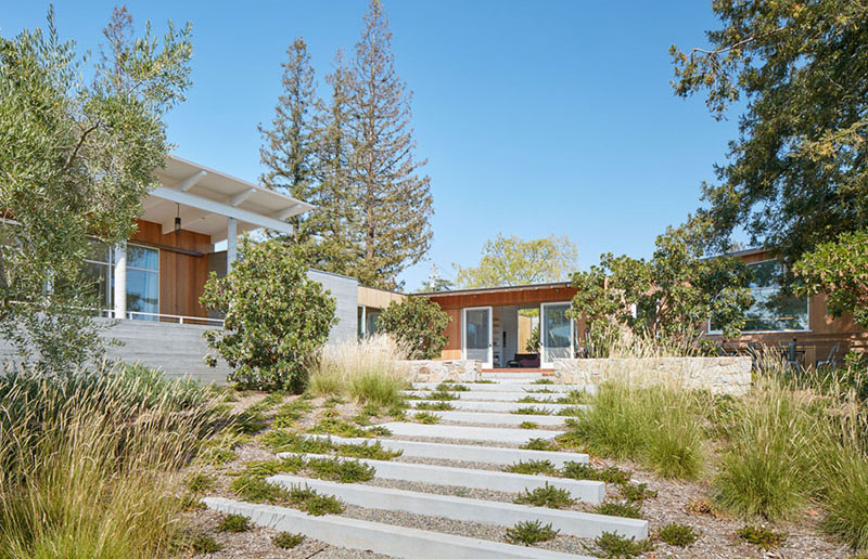 Since this home sits on a sloped site, landscaped paths guide movement across the property. Large stepping stones framed by ground cover create a garden-like walkway to the pool. Elsewhere, a dedicated firepit area invites gatherings around the warmth of an open flame.