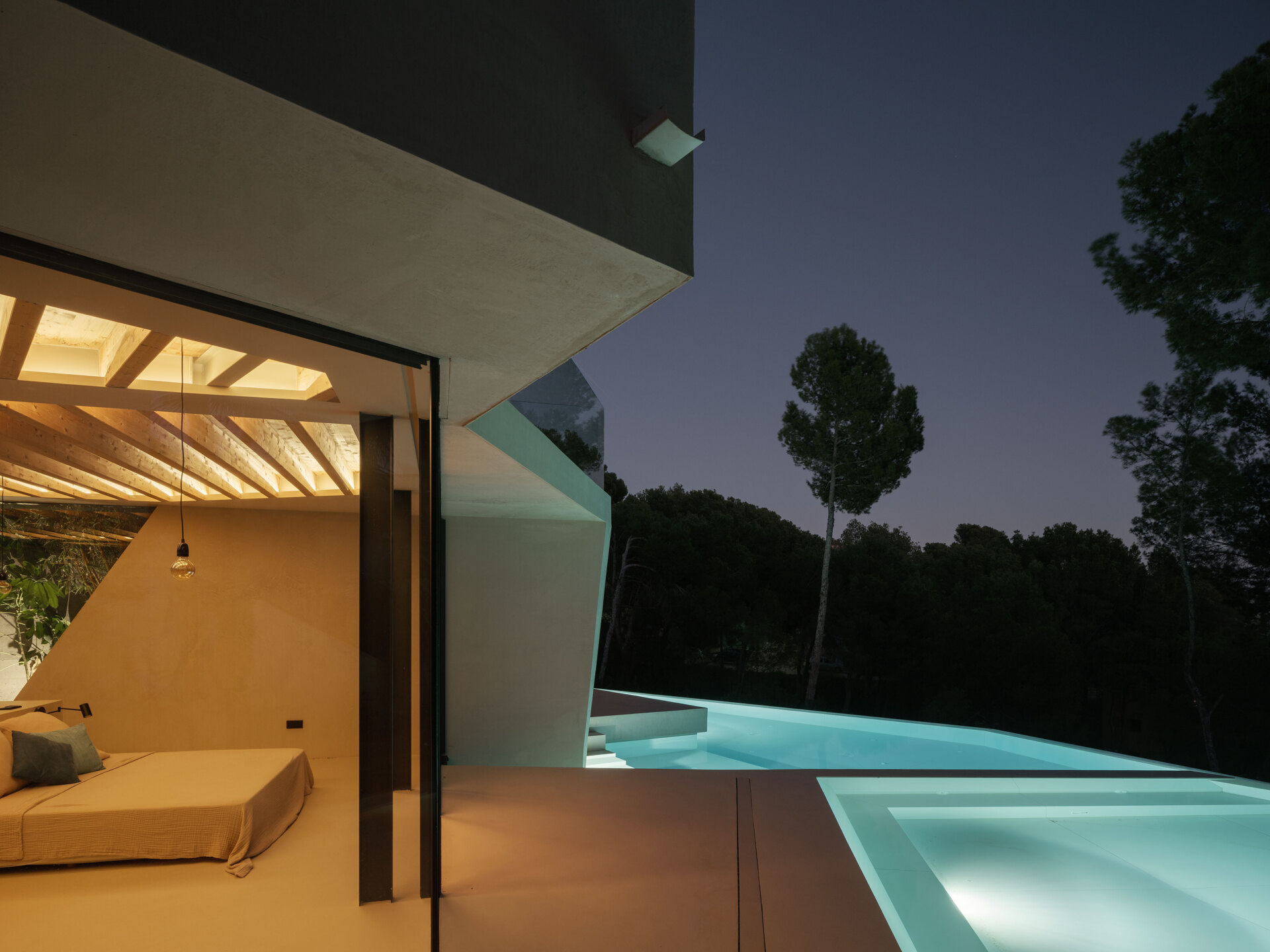 A hillside pool in Paguera frames the pine canopy and bay views, turning water and glass into a seamless extension of the home’s design.