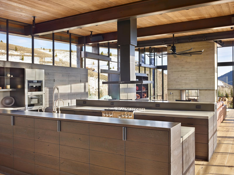 The modern industrial house kitchen is designed with dual islands, custom hardware, and pulley-hung lights, balancing functionality with striking style.