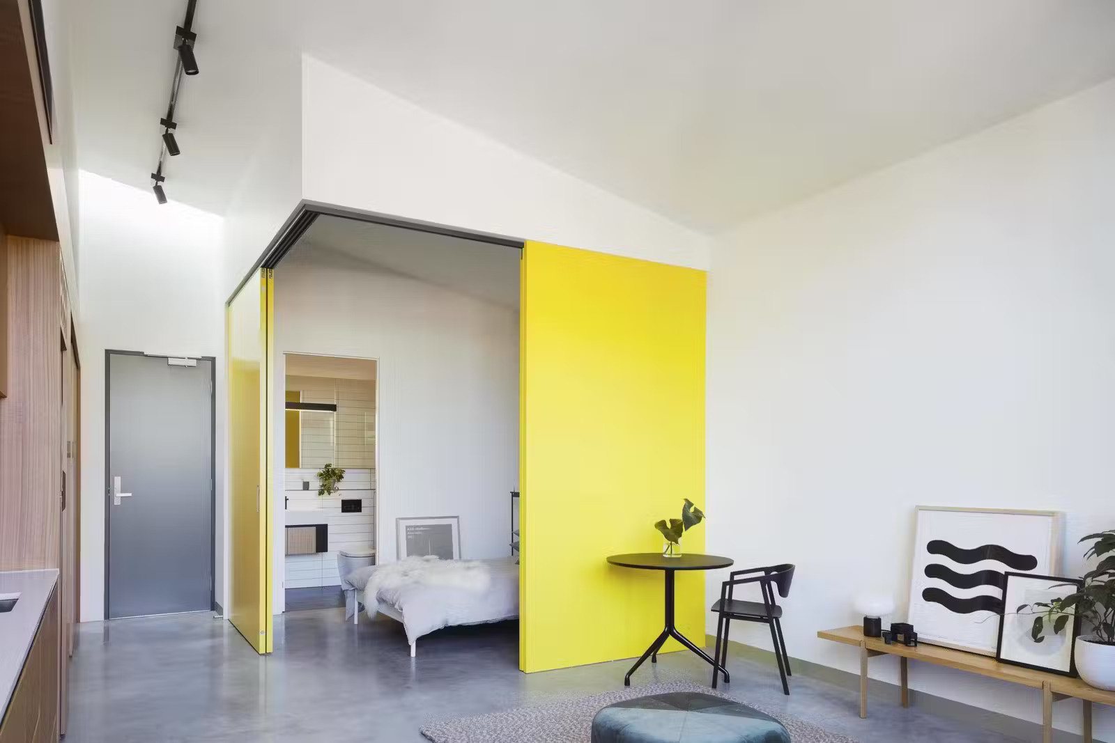 Bold yellow sliding doors reveal the bedroom while the living space flows into a private courtyard filled with natural light.