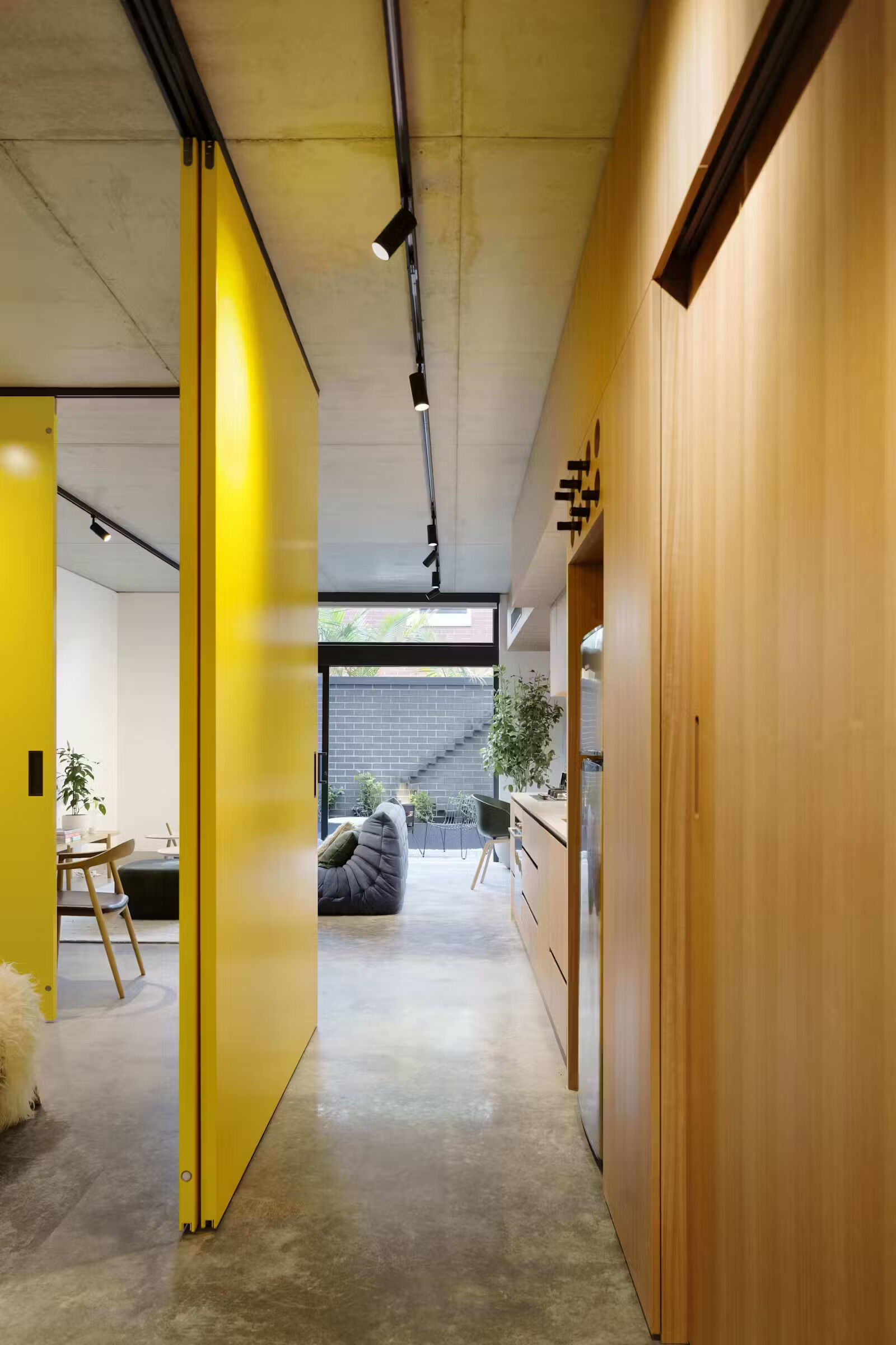 Bold yellow sliding doors reveal the bedroom while the living space flows into a private courtyard filled with natural light.