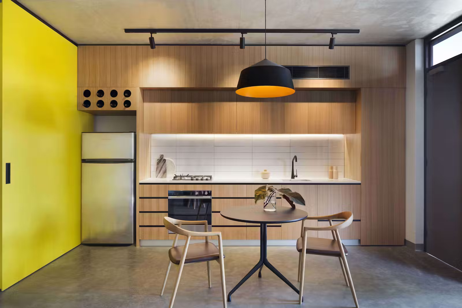 A clever kitchen design with a wine rack above the fridge makes a small apartment feel personal and well considered.