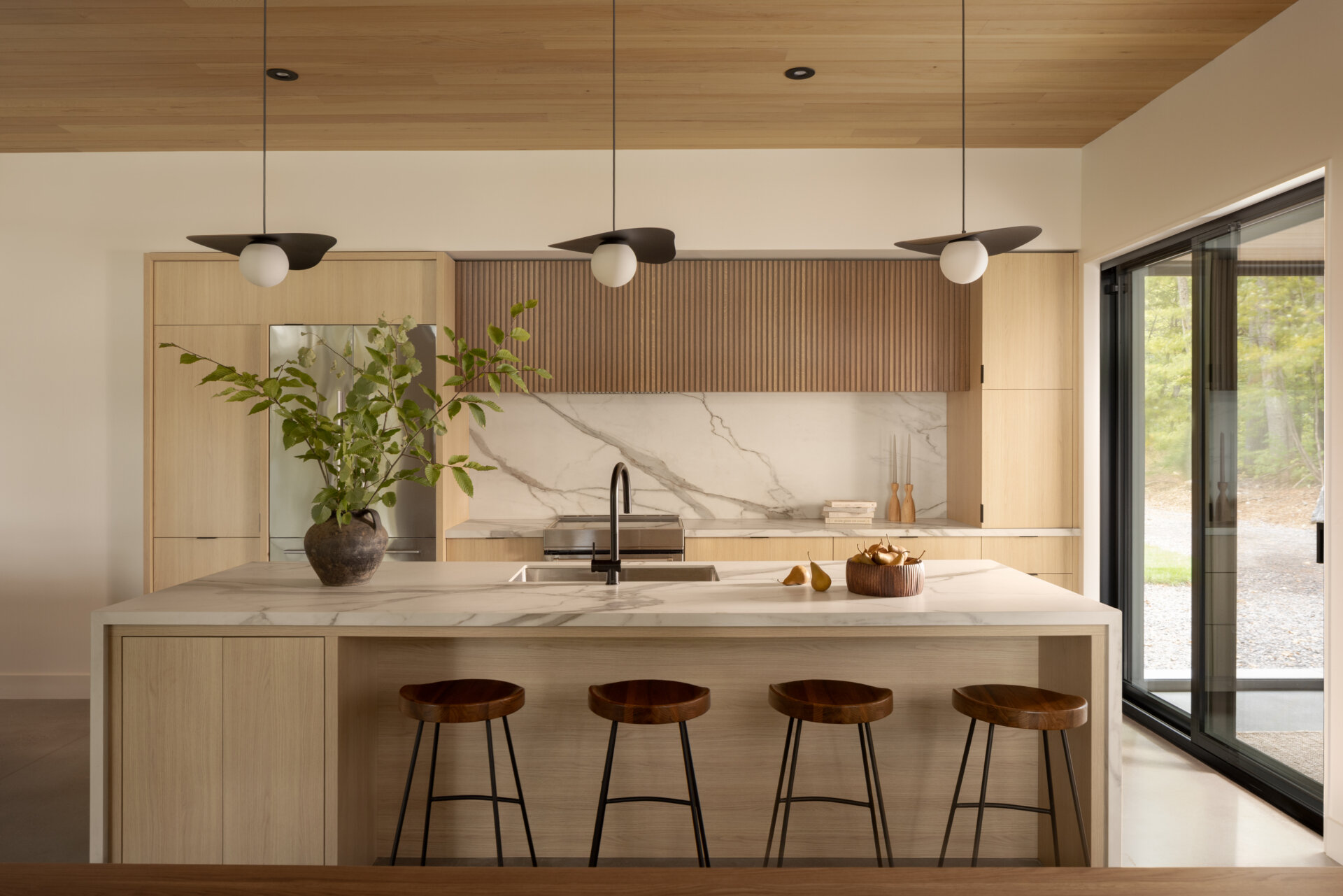 The kitchen, positioned alongside dining and office spaces, follows the same principle: openness to the lake. Here, everyday routines are connected to nature, with natural light softening the contrast between dark exterior and lighter interior tones.