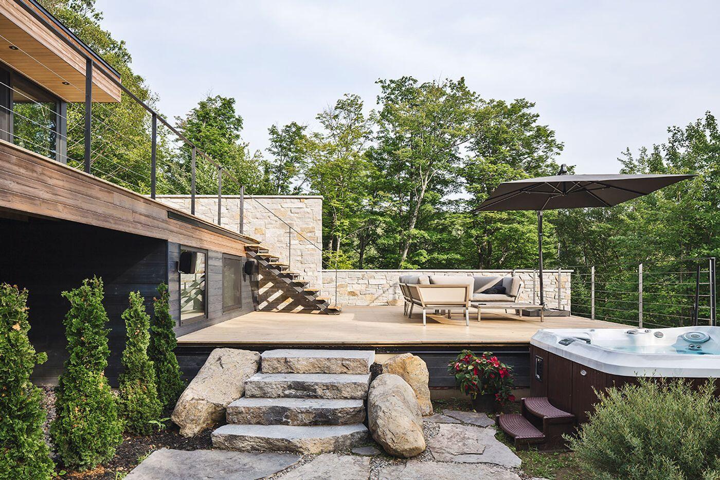 Terraced outdoor spaces framed by natural stone walls blend this modern home seamlessly into its rocky setting.