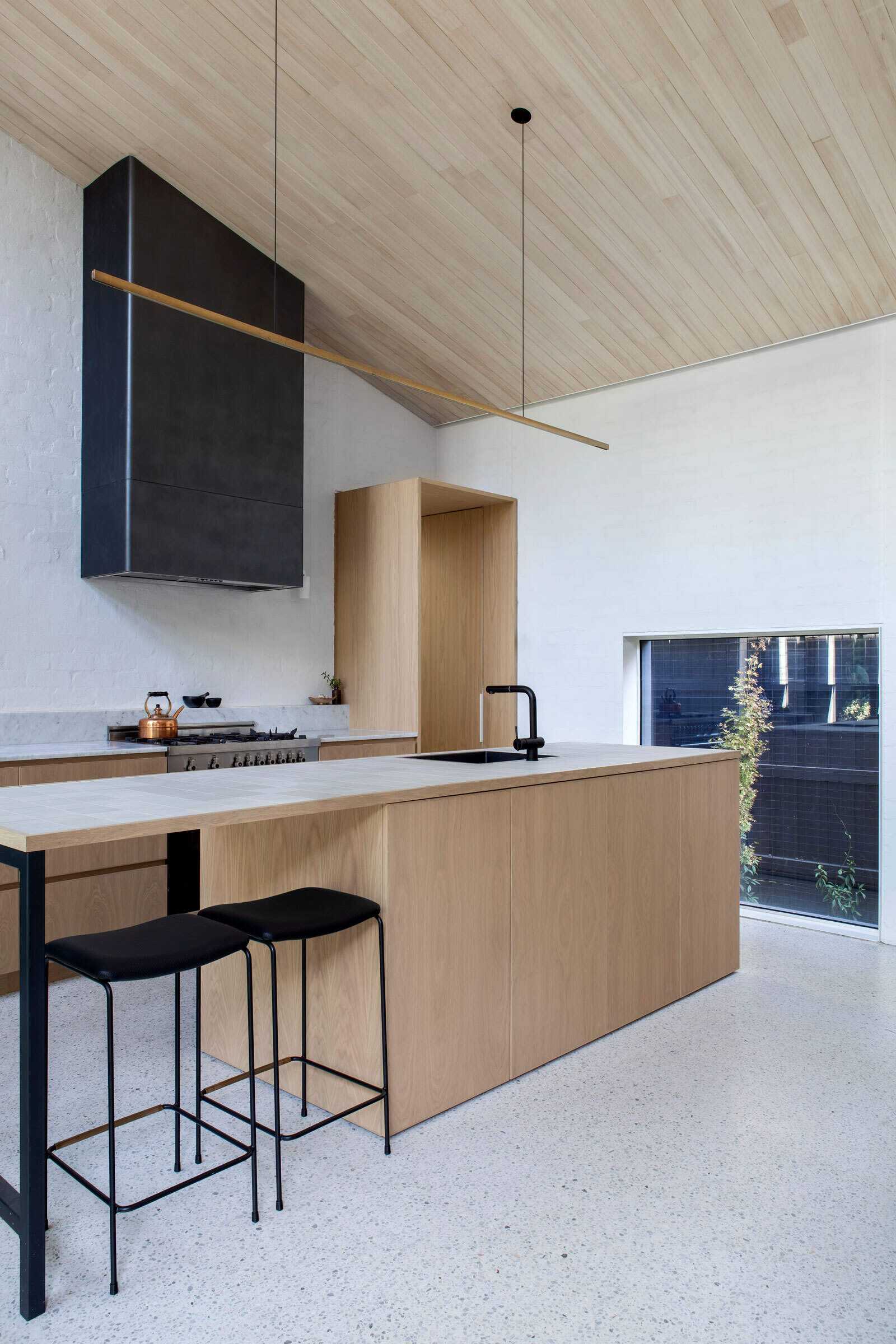 Light wood cabinets and countertops, accented with black details, create a fresh contemporary kitchen.