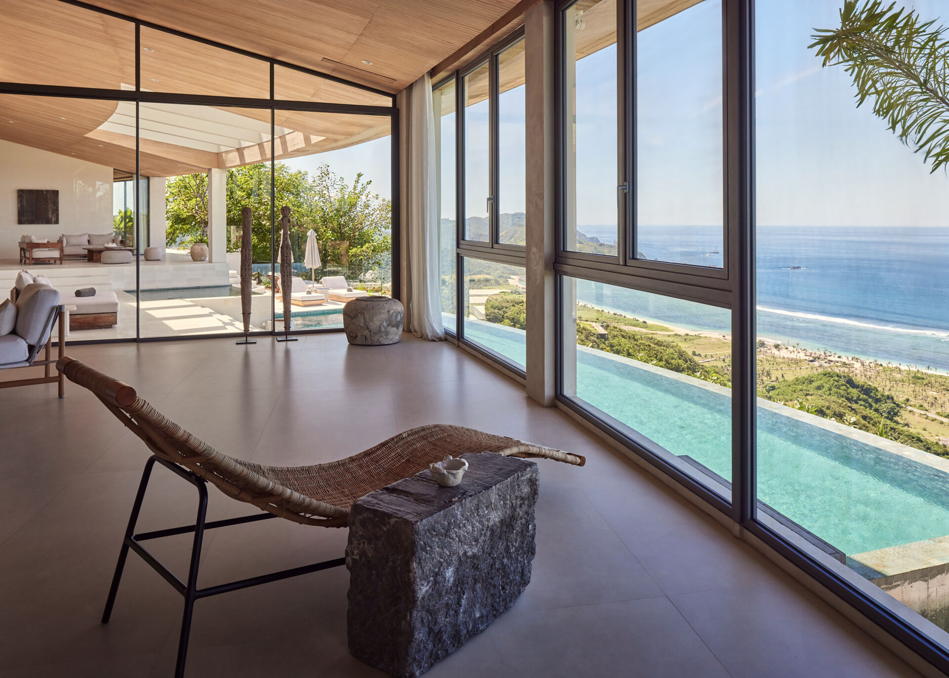The social areas open up after the entry, bringing together the living room, dining room, and kitchen. Walls of windows fills the interior with an abundance of natural light, while the wood ceiling and furniture adds warmth to the home.