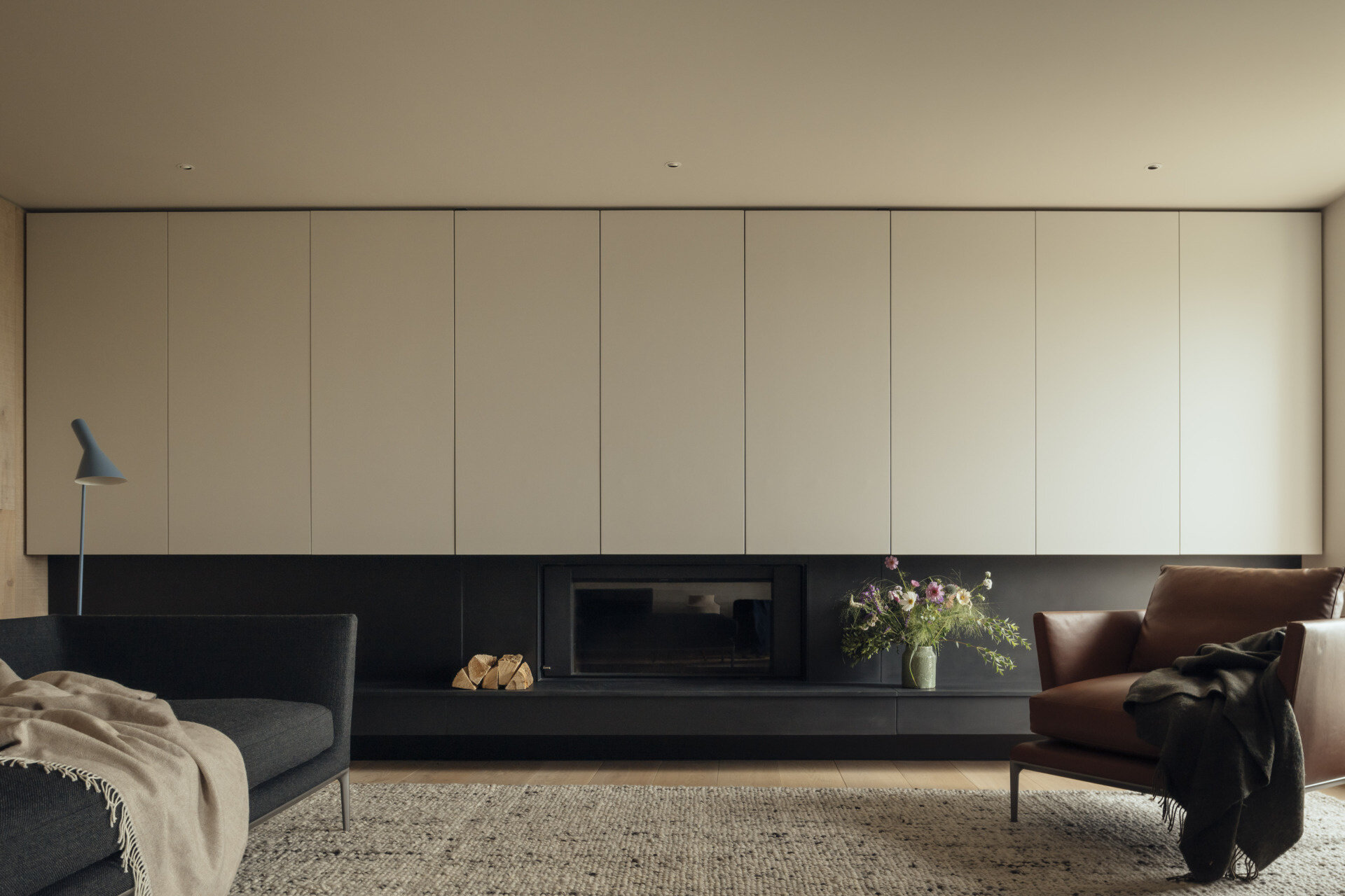 The living room takes full advantage of sweeping ocean and valley views. Walls of glass flood the interior with natural light, creating a space that feels close to the elements while sheltered from the coastal winds. The room connects seamlessly to terraces at the front and rear, extending the living experience into the landscape.
