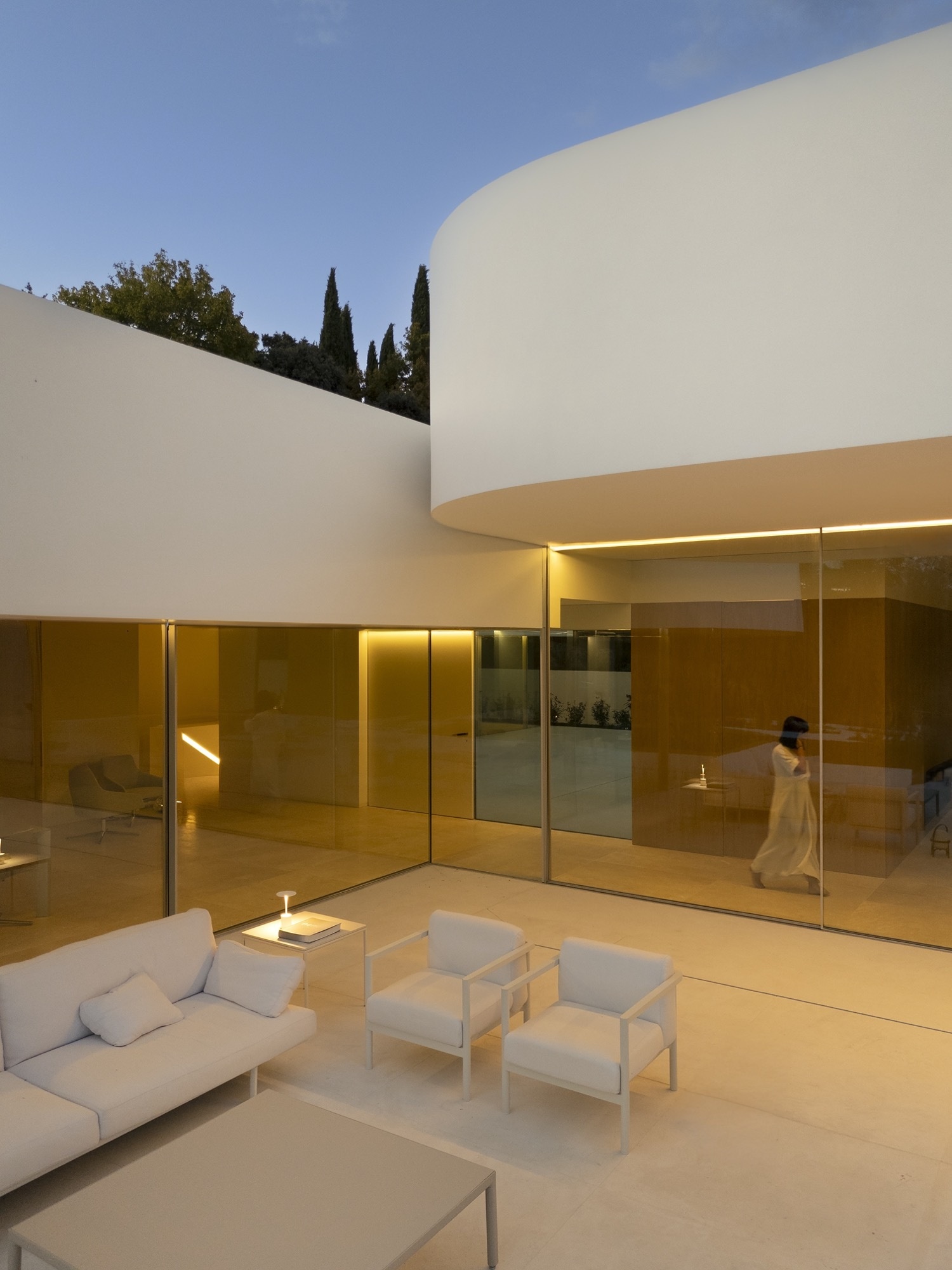 The sheltered terrace, formed by the shifted volumes, is oriented toward the southeast landscape. Curved edges define its open-air spaces, blending fluidly with the straight lines of the home’s geometry. This creates both a comfortable outdoor environment and continuity between interior and exterior.