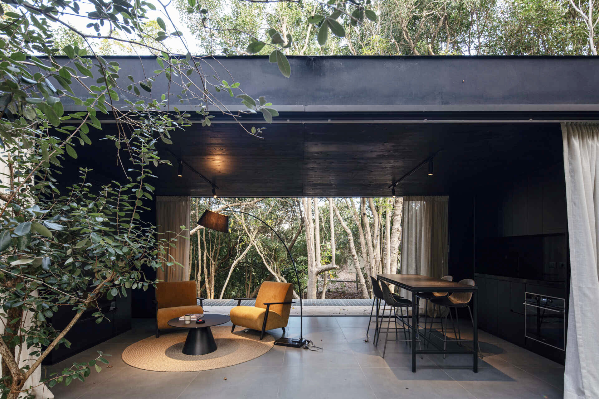 A small prefab home has sliding panels that blur the boundaries between indoors and outdoors, allowing the social space to open fully on both sides.