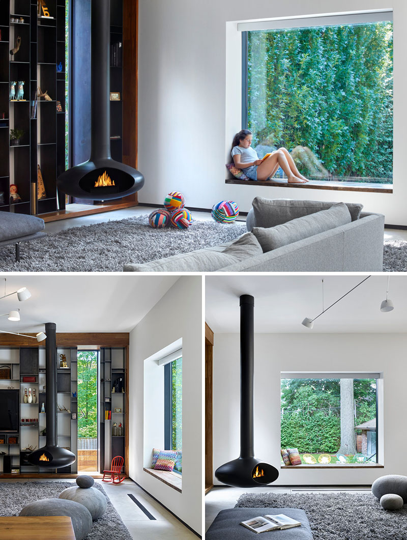 A modern bay window frames backyard views and includes a custom wooden bench that matches the dining table. Patterned cushions add comfort and a splash of color to the neutral backdrop.