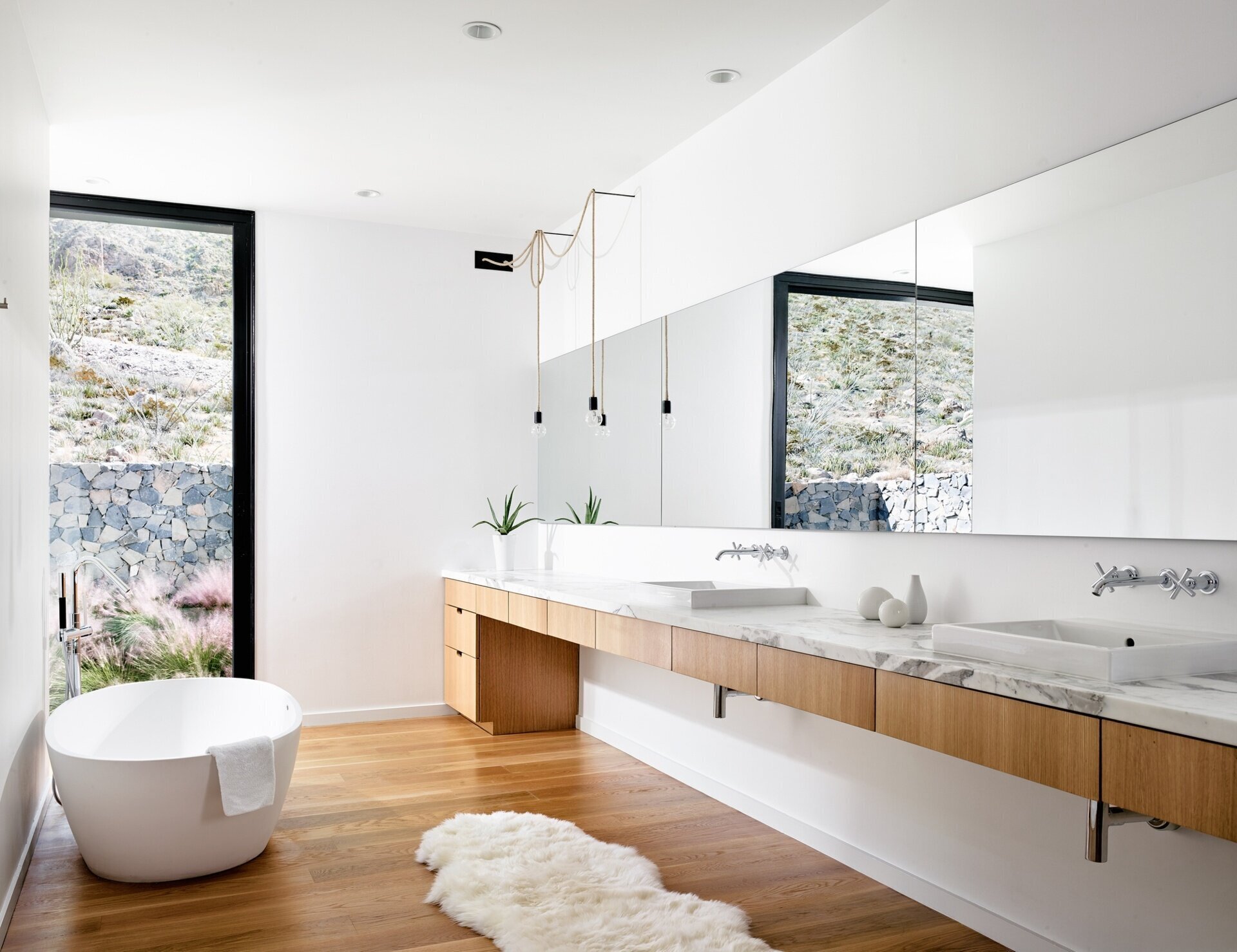 Bright and airy, the master bathroom of this modern mountain home pairs oak cabinetry with marble surfaces.