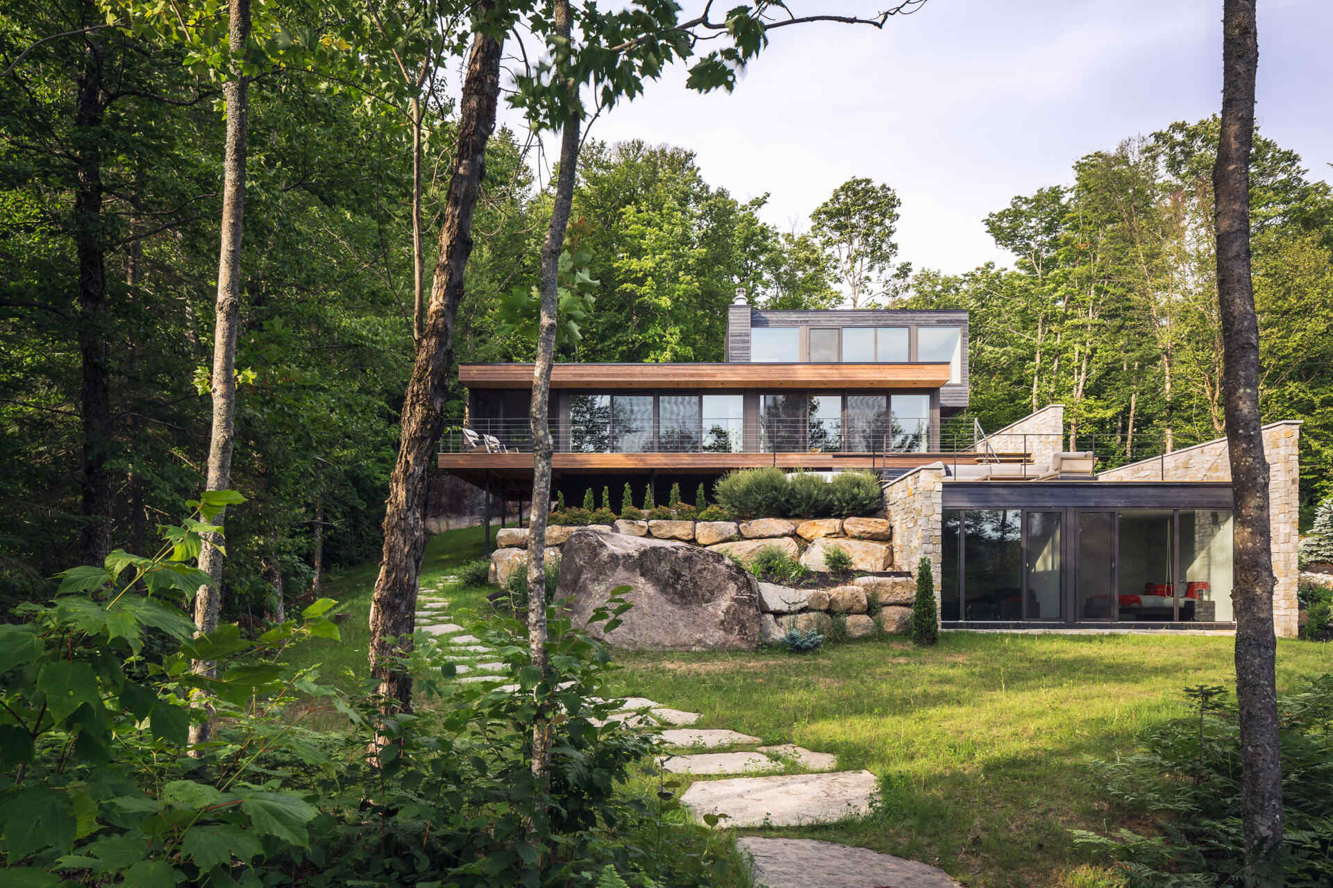 Terraced outdoor spaces framed by natural stone walls blend this modern home seamlessly into its rocky setting.