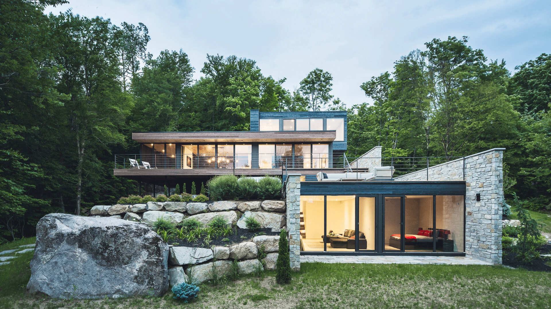 Terraced outdoor spaces framed by natural stone walls blend this modern home seamlessly into its rocky setting.