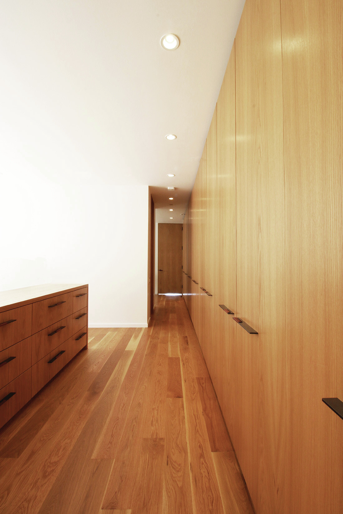 A serene master bedroom with oak finishes and sliding doors to a desert patio inside a modern mountain home.