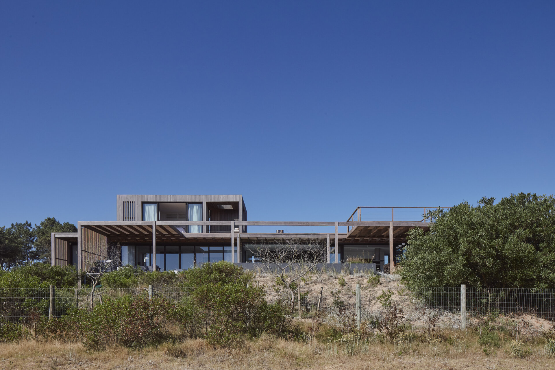 This prefabricated modular house, clad in wood, preserves the sandy terrain while opening all rooms toward the sea.