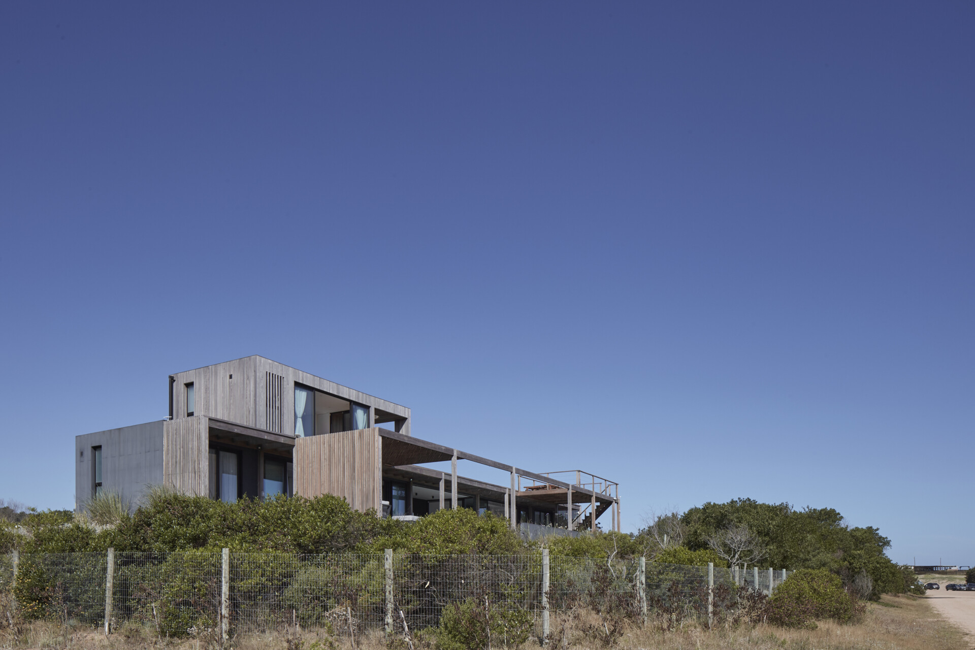This prefabricated modular house, clad in wood, preserves the sandy terrain while opening all rooms toward the sea.