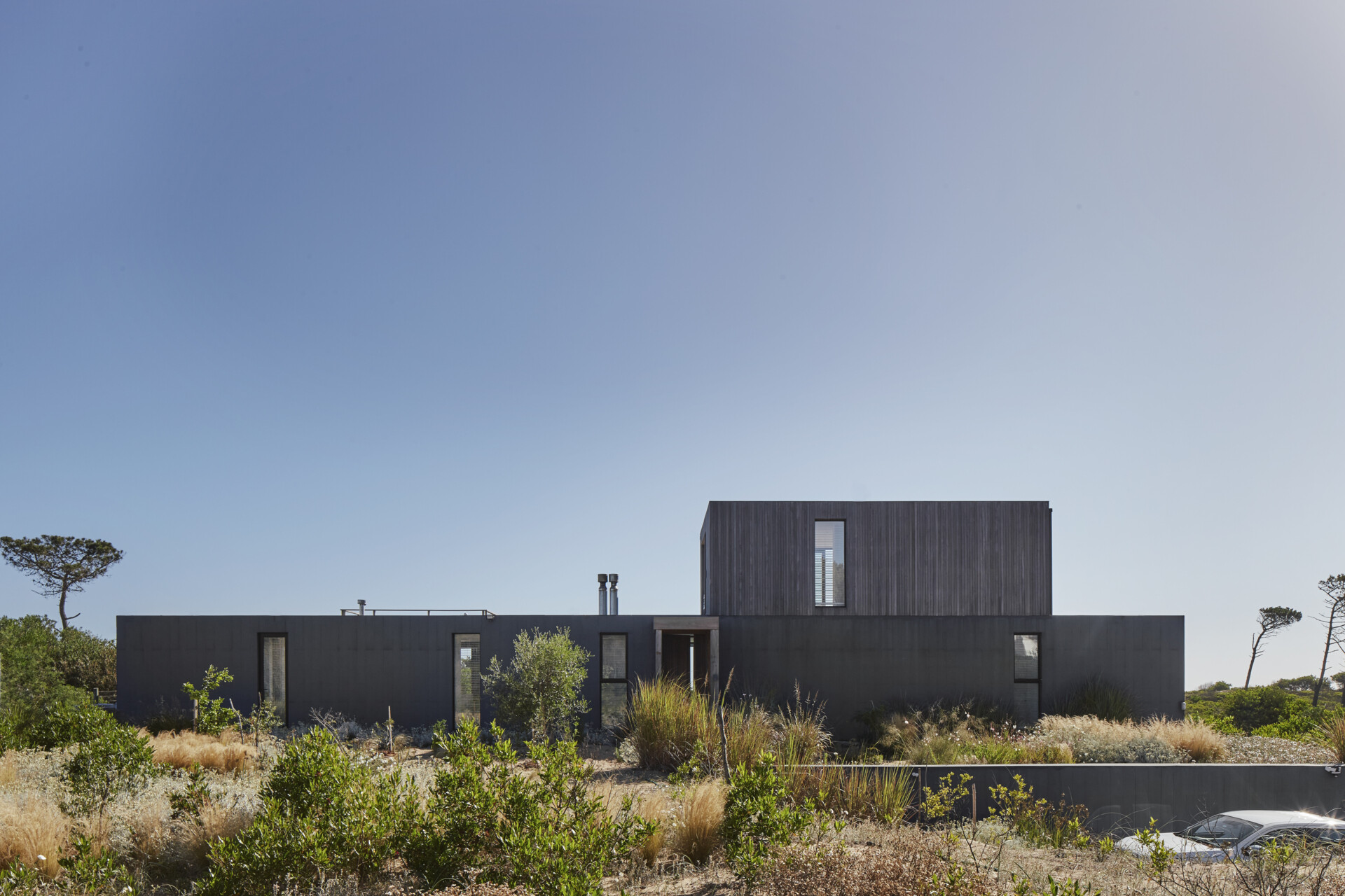 This prefabricated modular house, clad in wood, preserves the sandy terrain while opening all rooms toward the sea.