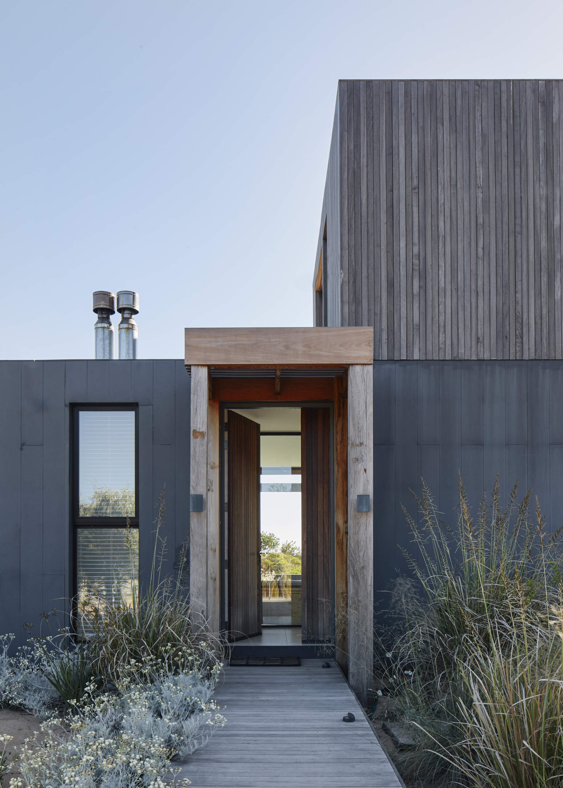 This prefabricated modular house, clad in wood, preserves the sandy terrain while opening all rooms toward the sea.