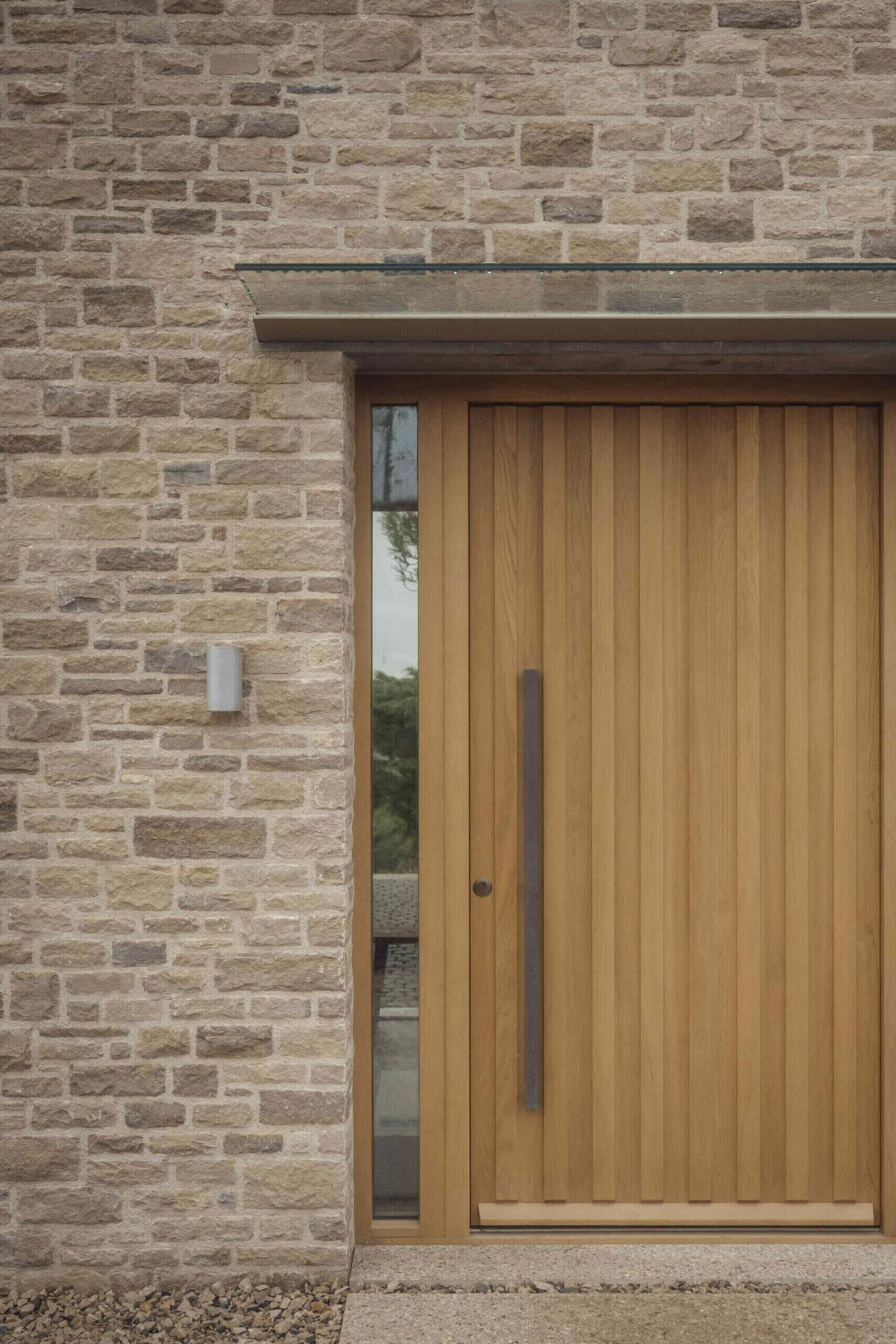 The wood front door opens to an entry hall with floor-to-ceiling glass overlooking a sheltered courtyard.