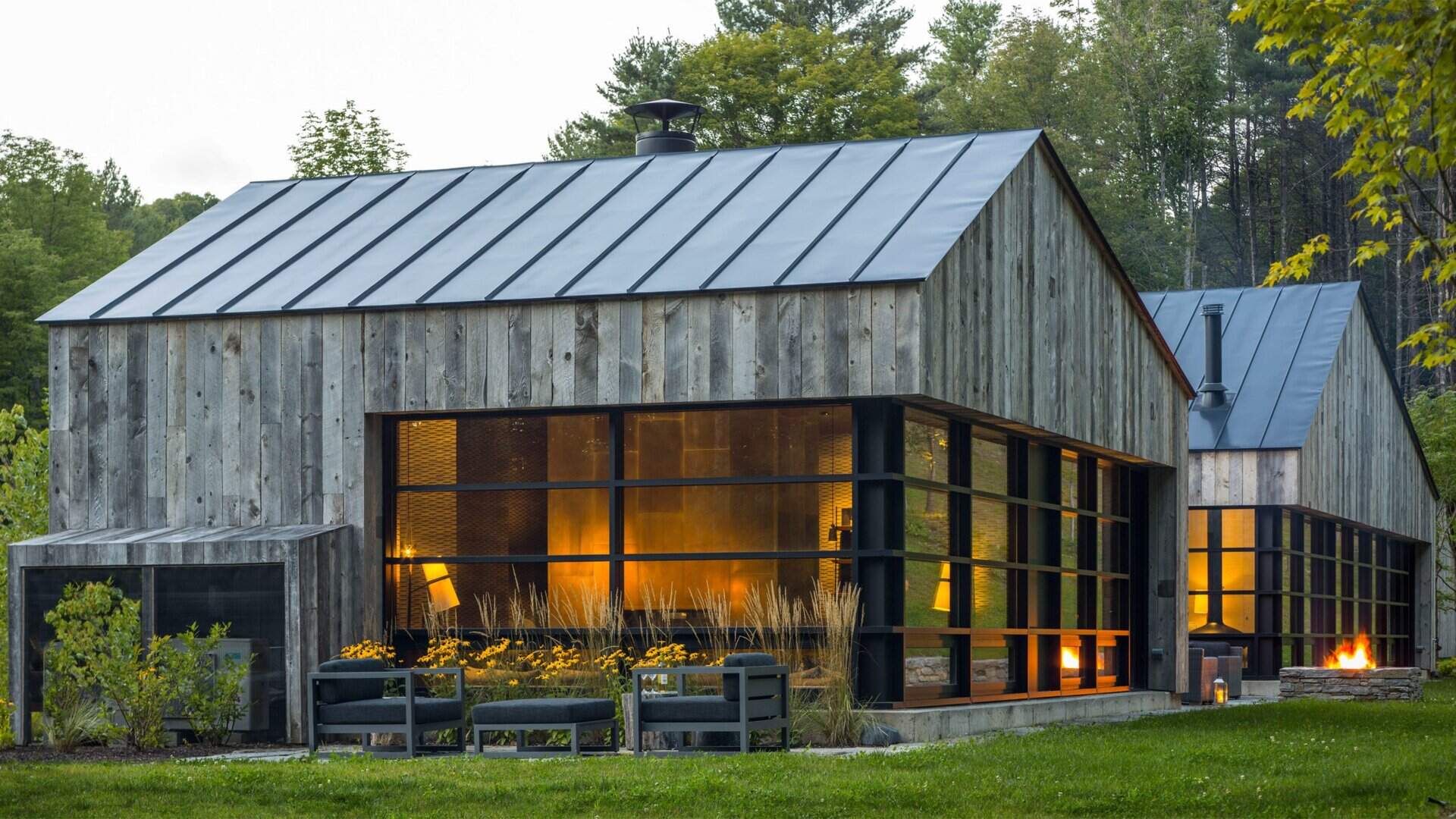 A Vermont guest house takes its shape from the classic woodshed, with gabled roofs that reimagine a familiar rural form. The house is clad in reclaimed snow fencing, weathered boards that give the structure instant character and texture.