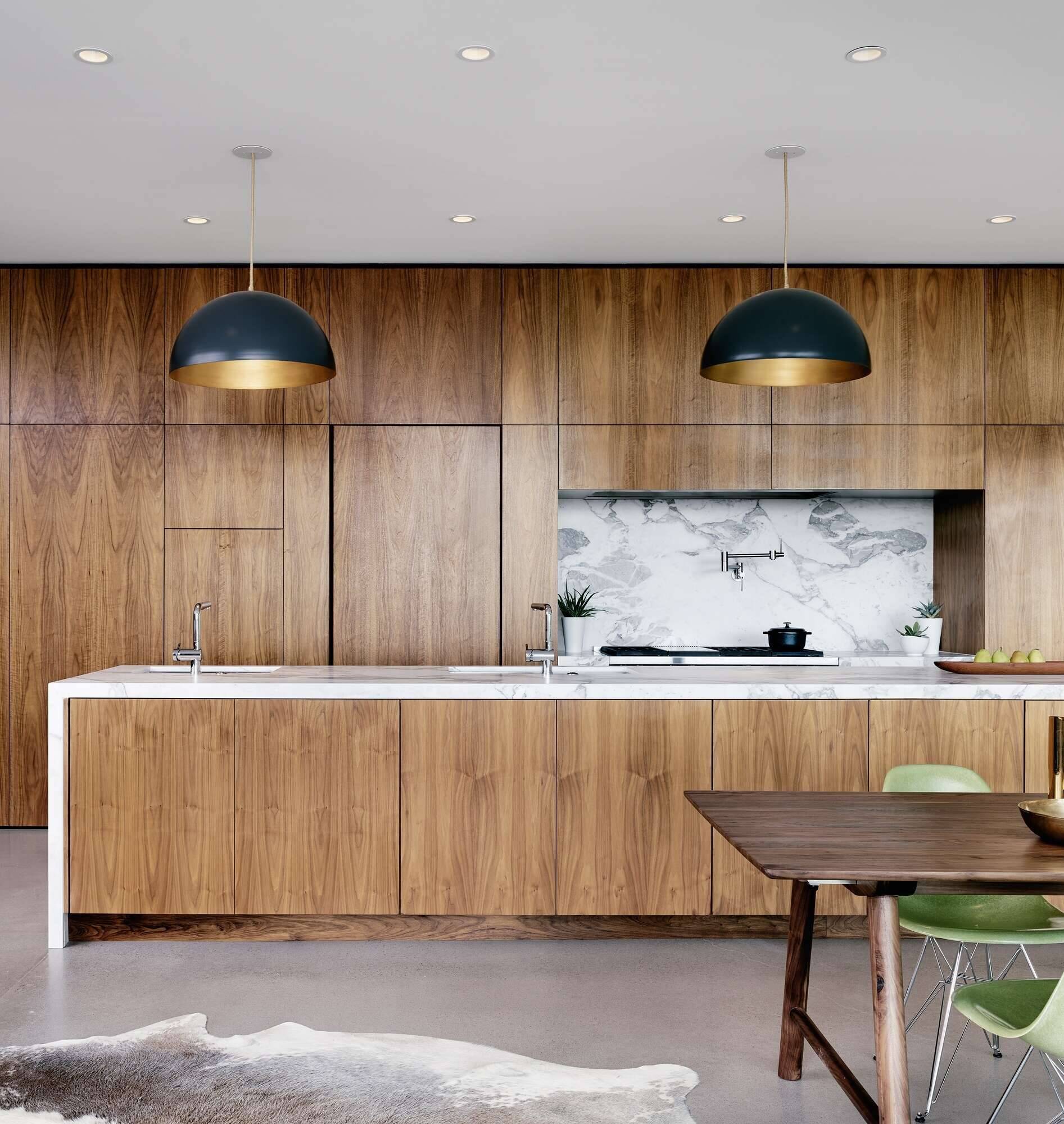 Polished concrete floors, walnut cabinetry, and marble accents define the kitchen of this modern mountain home.