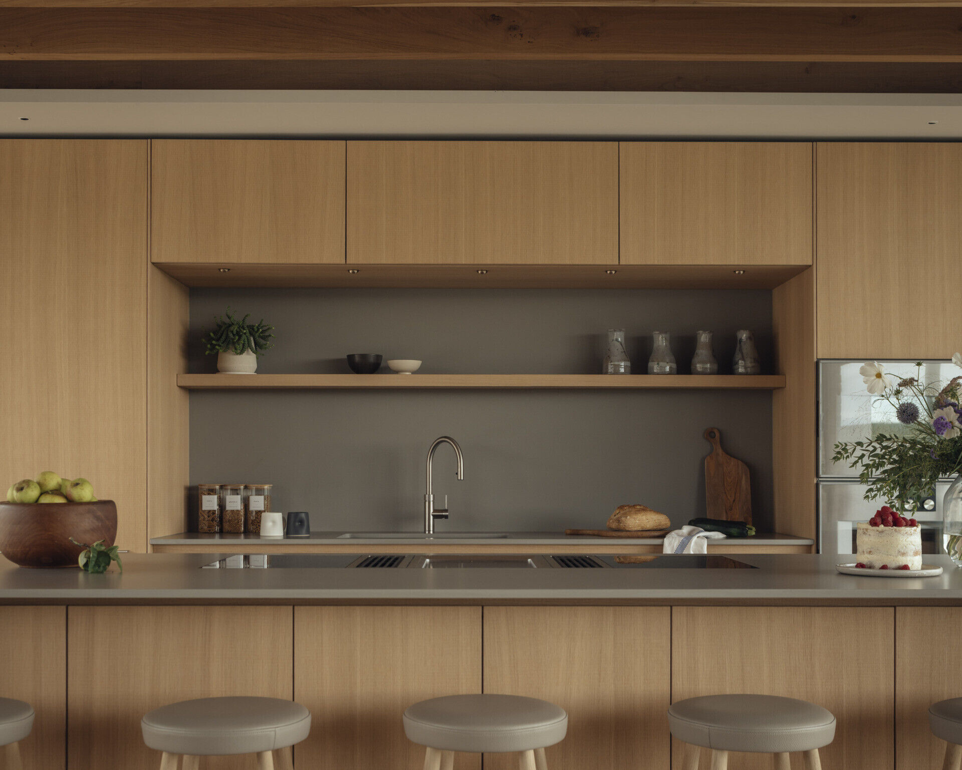 The kitchen blends function with crafted detail. McLean Quinlan’s custom joinery appears here in smooth and rough-sawn oak, paired with brushed brass hardware. The flooring is engineered oak, offset by plaster walls and large ceramic tiles that provide both texture and warmth. The design ensures practicality while retaining a sense of tactile luxury.