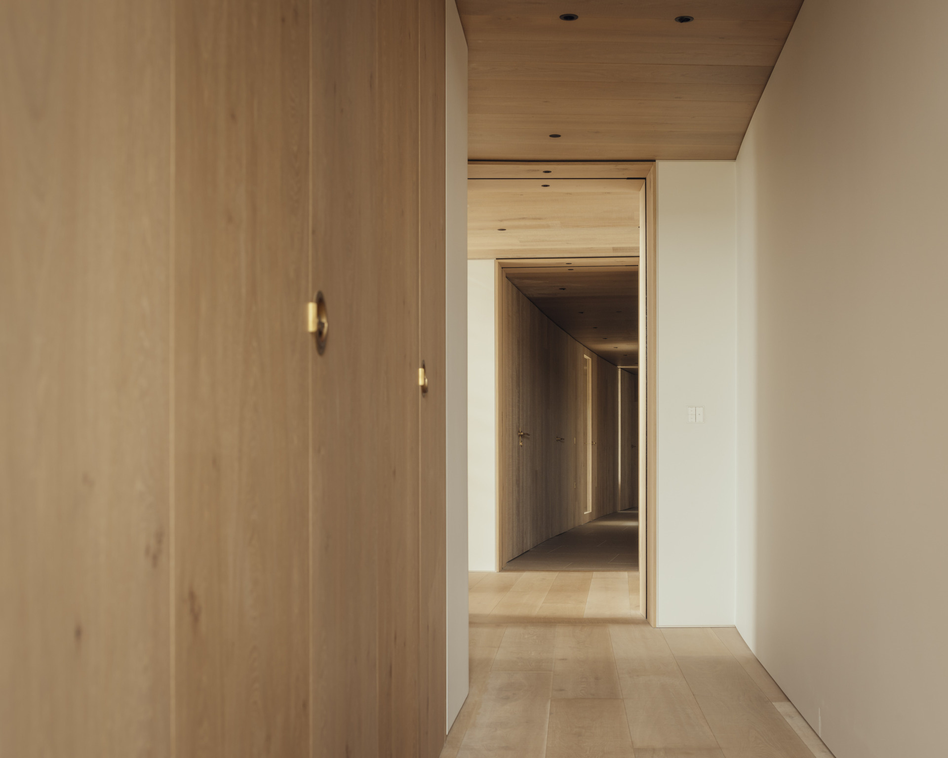 Circulation is designed as an experience. Deep inset windows and wood line the hallways, framing coastal and farmland views. Each transition through the home reveals new perspectives of the landscape.