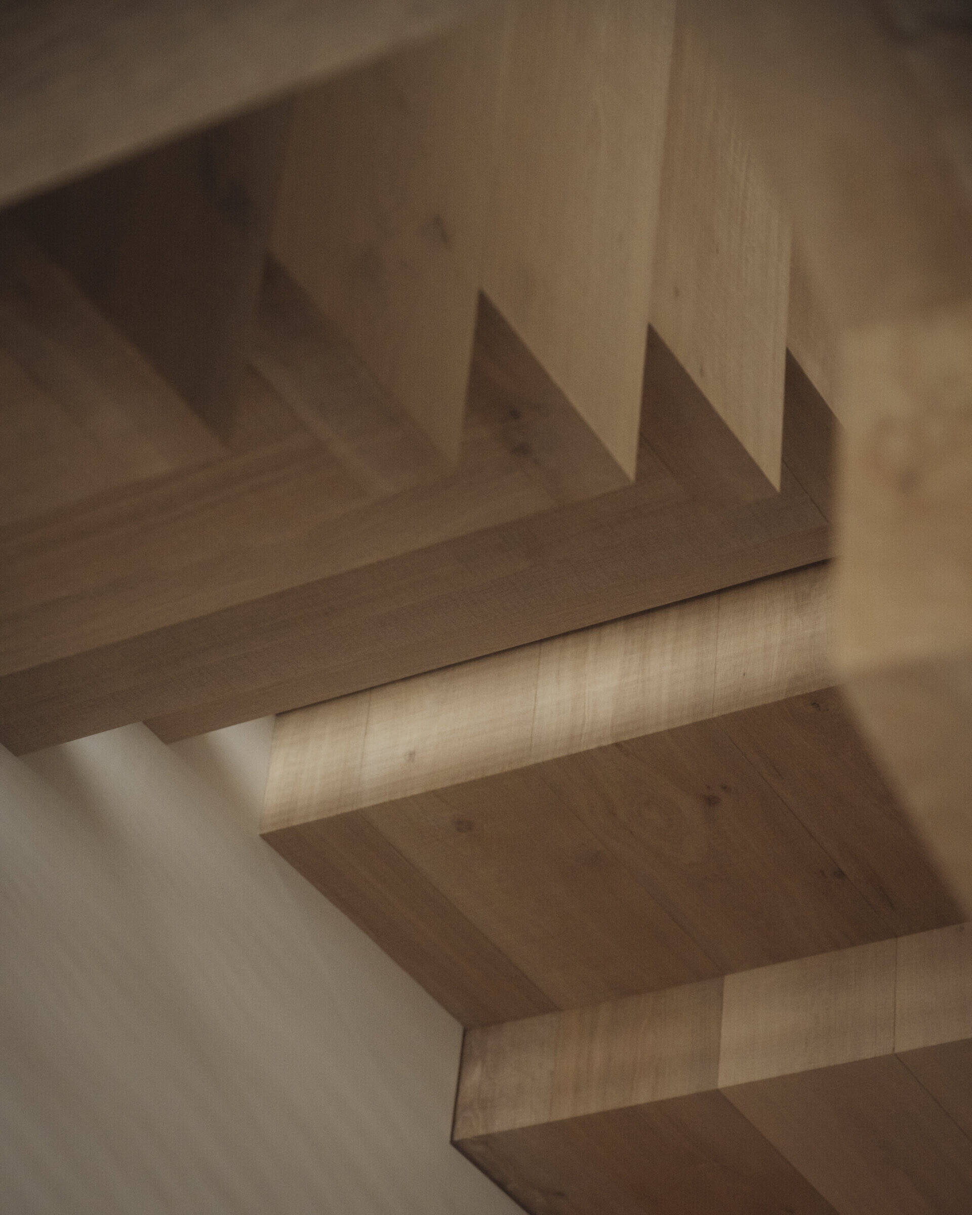 At the south side of the house, a stair hall becomes an architectural feature in itself. Glazed walls bring in daylight, while angled oak slats filter sun and add rhythm to the stone facade. Oak treads connect the levels, carrying light between floors.