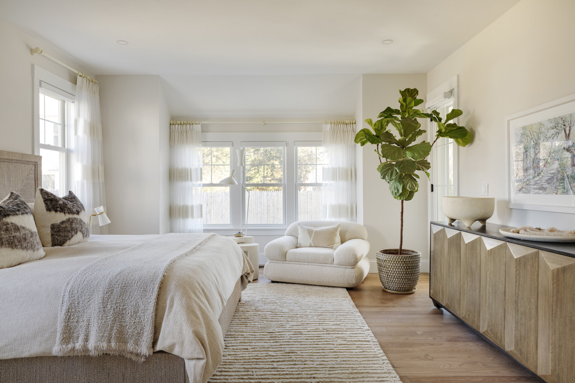 In the bedrooms of this Cape Cod home, the clients’ sentimental artwork was carefully reframed to give each piece a fresh, modern presence that complements the new design. Natural materials like wicker and rattan, gentle pops of green, and softly curved furniture tie the rooms to the coastal surroundings.
